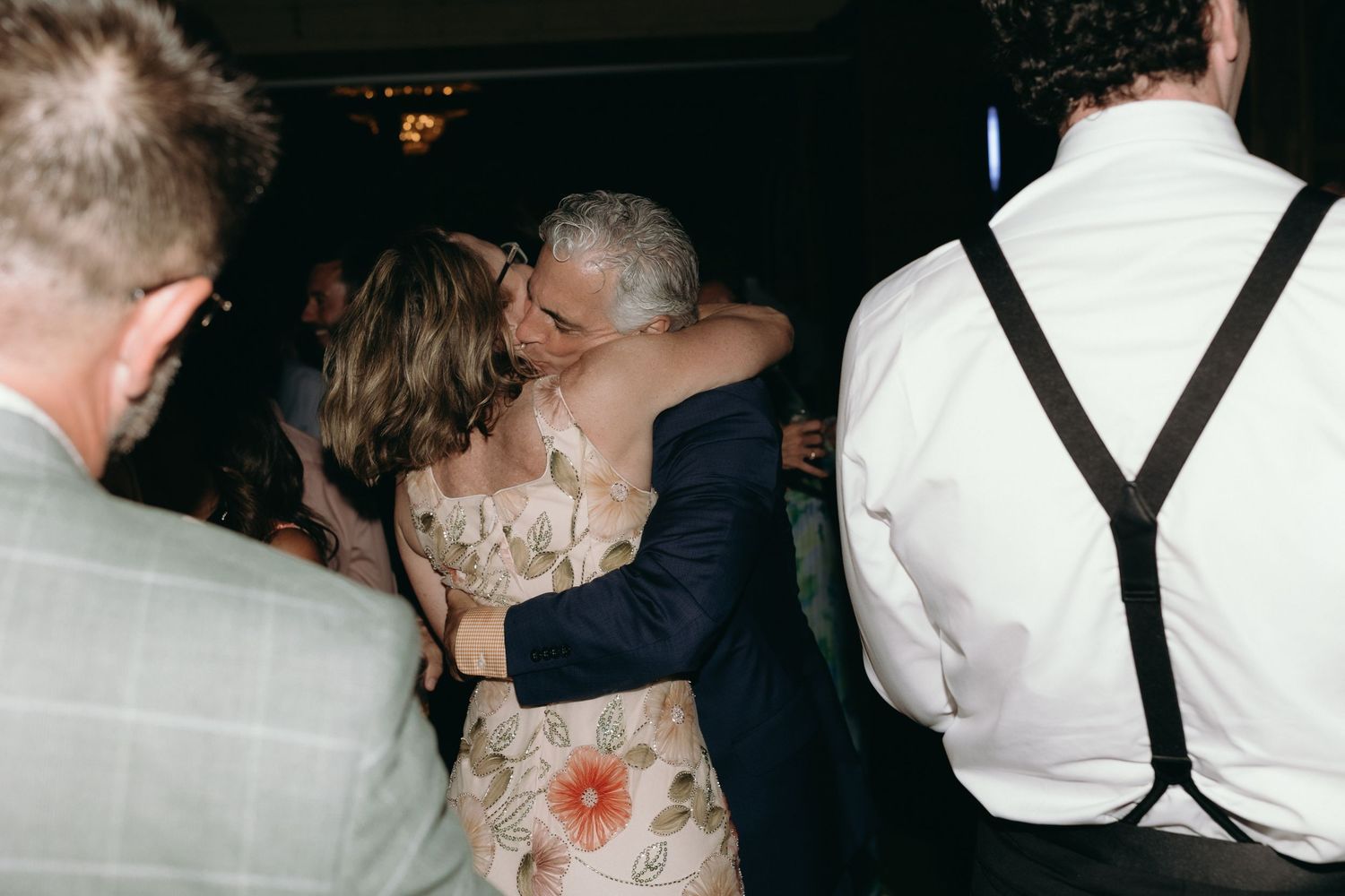 Couple sharing a warm embrace while dancing closely together at a lively wedding reception.