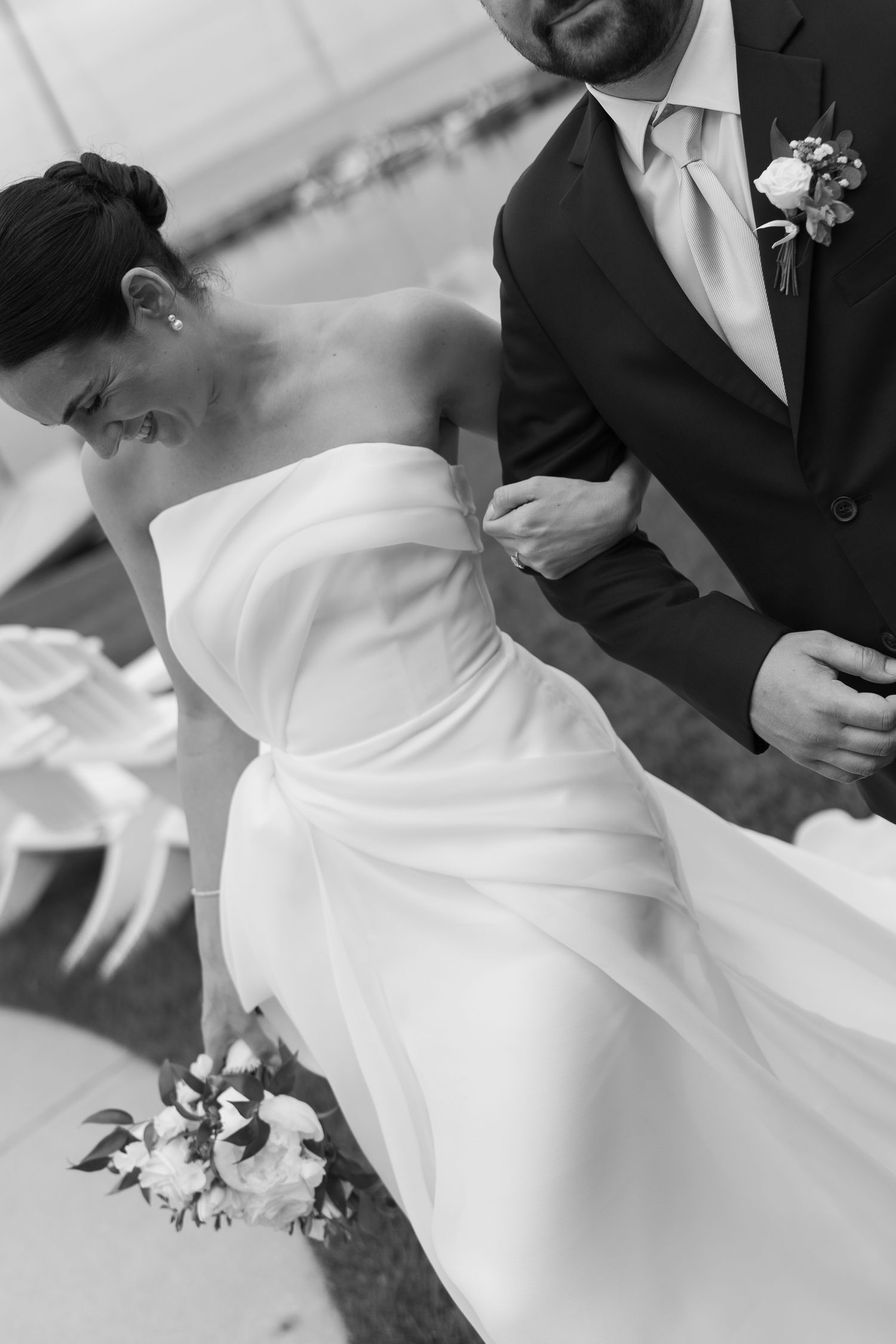 A black and white wedding photo showing a couple where the bride wears a classic white strapless gown and groom in dark suit.