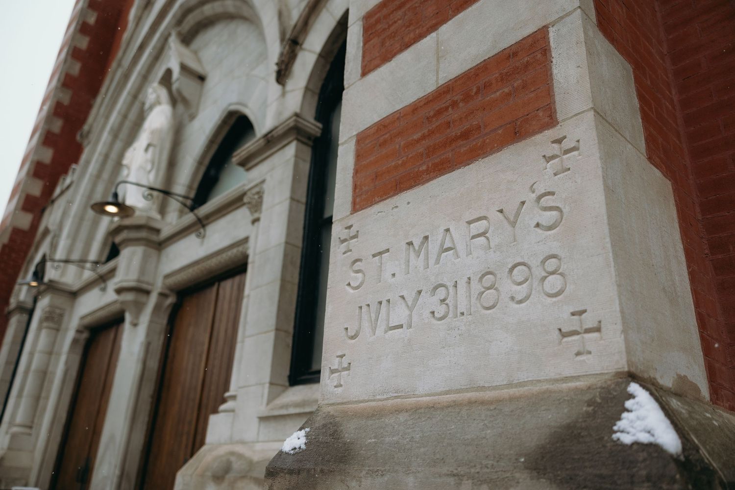 Historic architectural detail showing carved stone text and arches on a brick building.