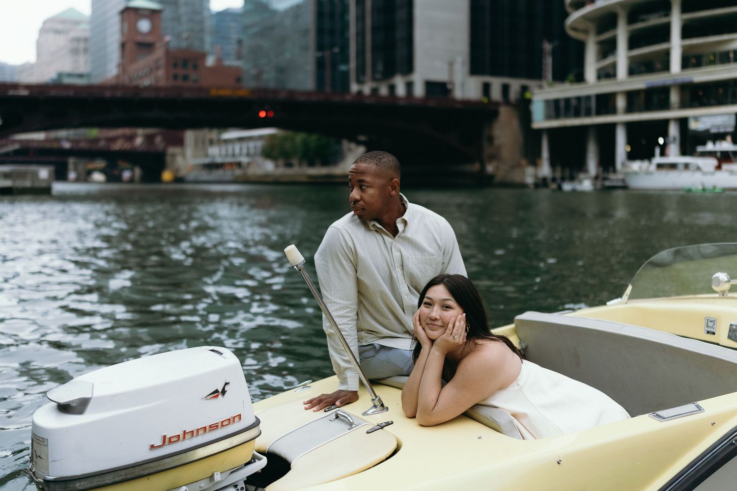 Couple enjoying a romantic boat ride on a city river, smiling and relaxed on a yellow vintage speedboat.