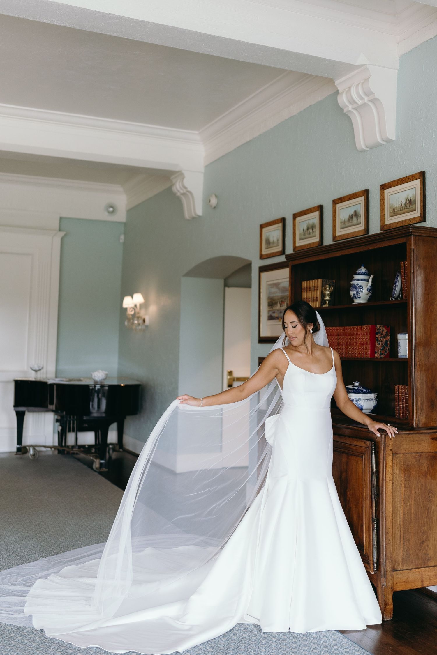 Elegant white wedding dress being displayed in a room with vintage furniture and artwork.