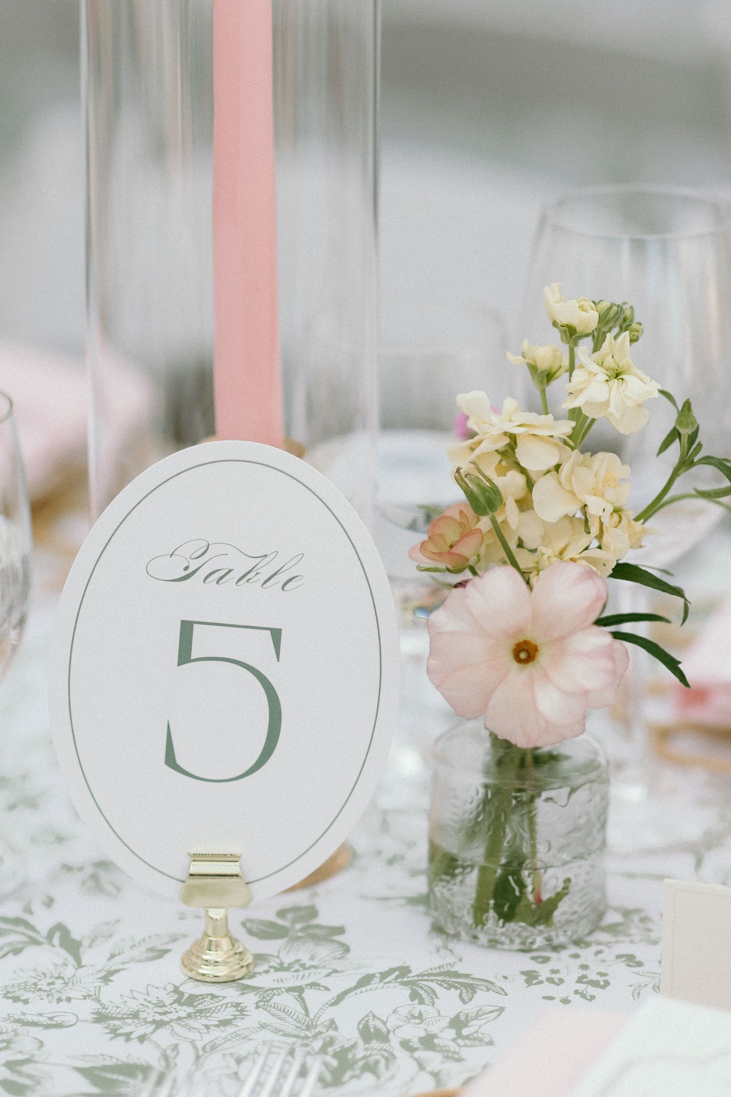 Minimalist wedding Table 5 sign displayed beside a small vase of soft pink and white flowers.