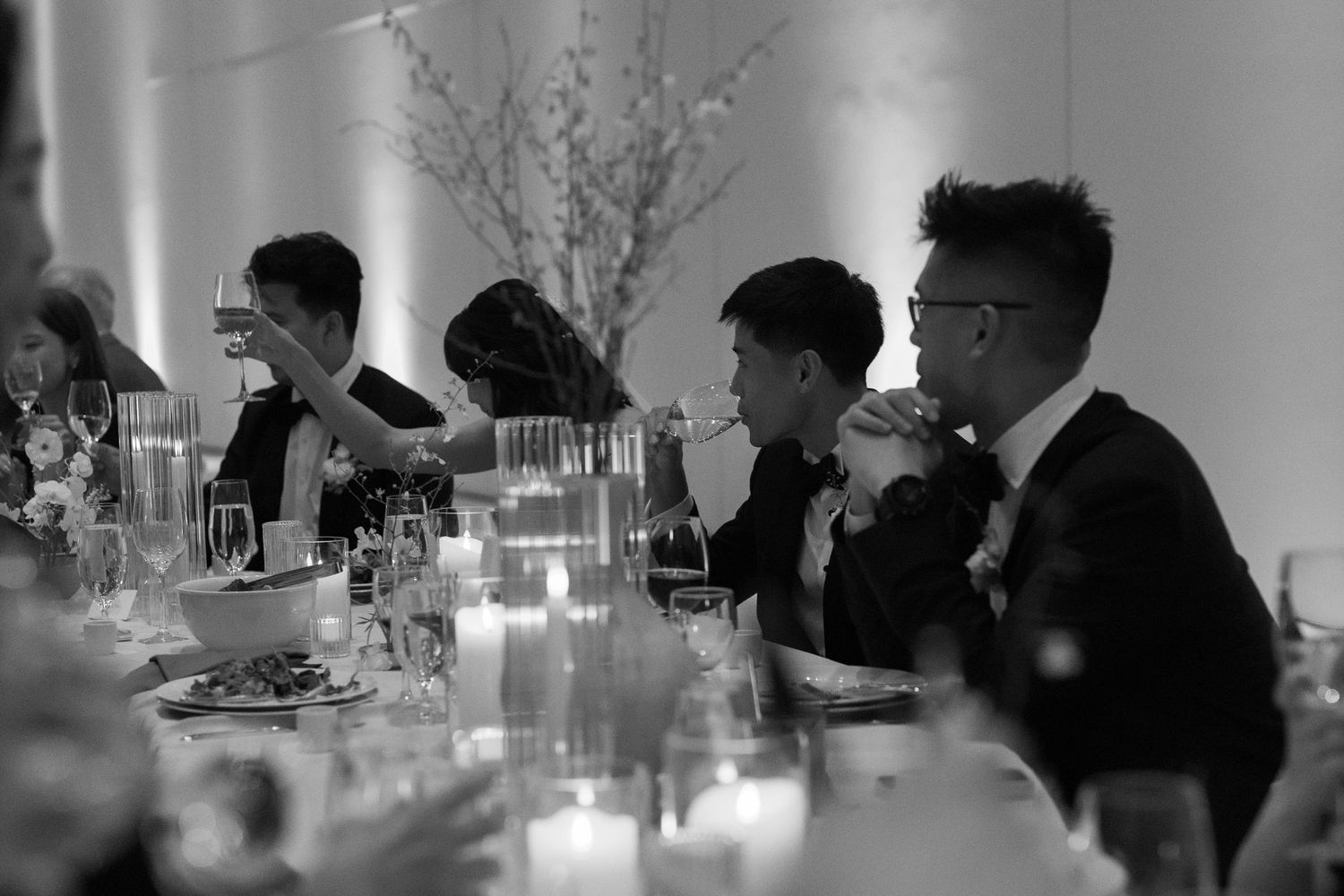 Dimly lit reception dinner with guests seated at long tables.