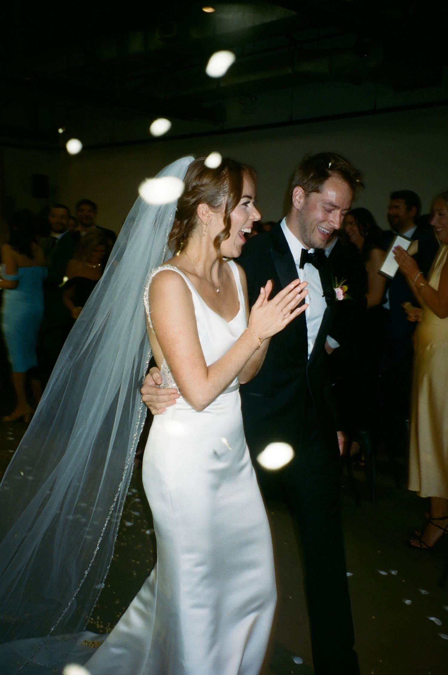 Couple shares a romantic dance at their wedding reception while guests look on in the background.