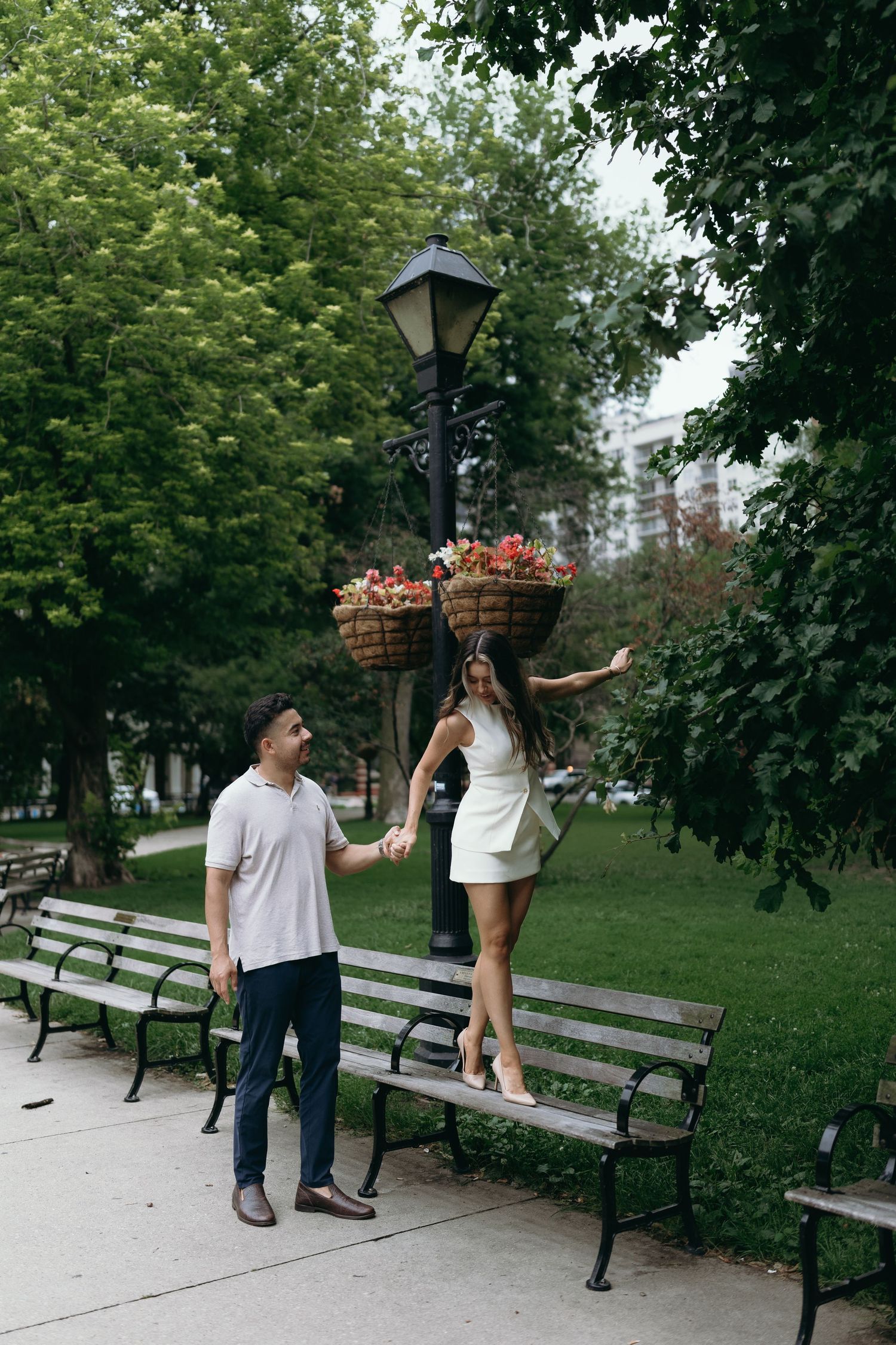 A couple enjoys a romantic moment in a Chicago Gold Coast park with vintage benches and a lamppost on a summer day.