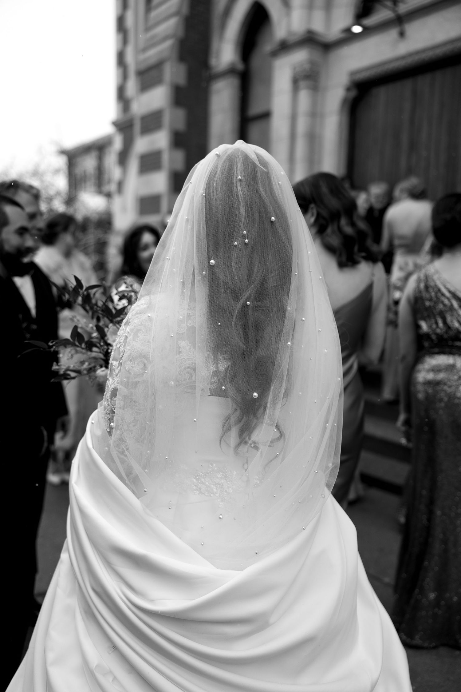 Black and white photo showing detailed back view of bridal veil with delicate embellishments.