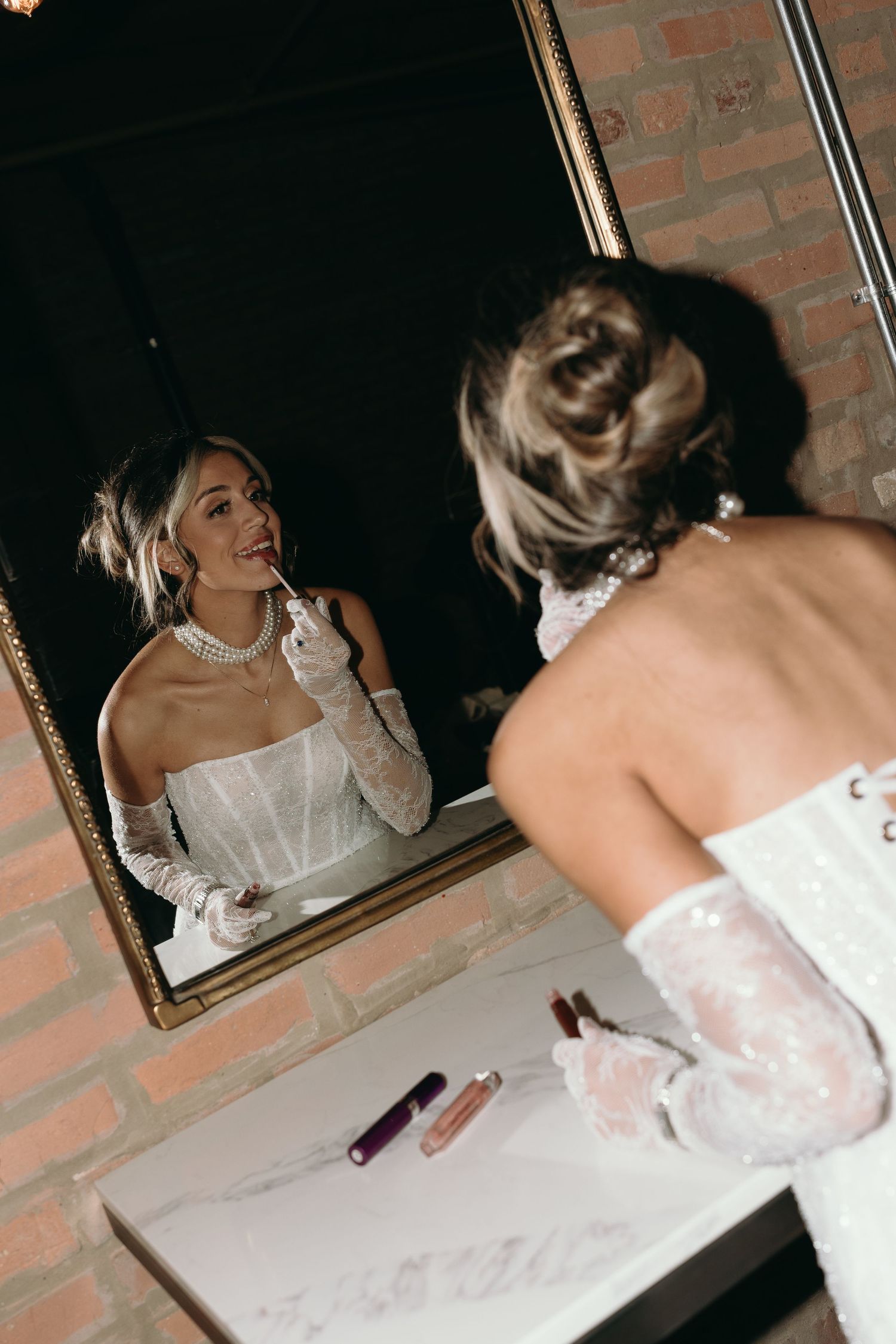 A sequence of images showing someone in a white dress looking at their reflection in a mirror against a brick wall.