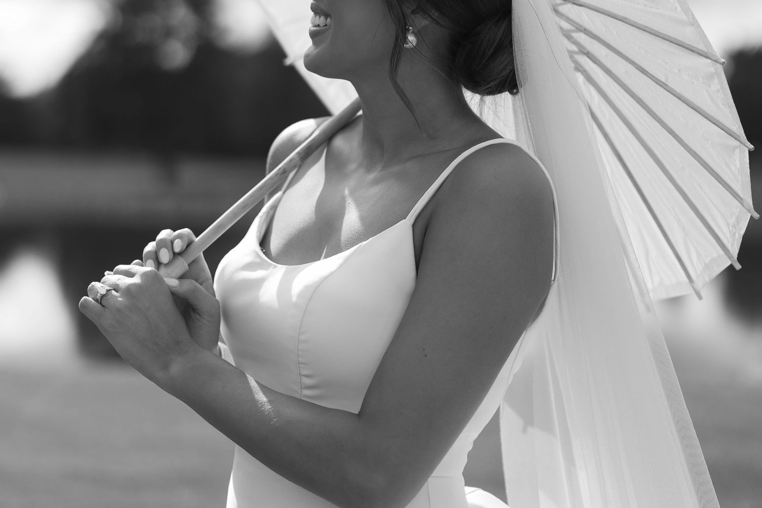 Black and white portrait with white parasol and sleek wedding dress.