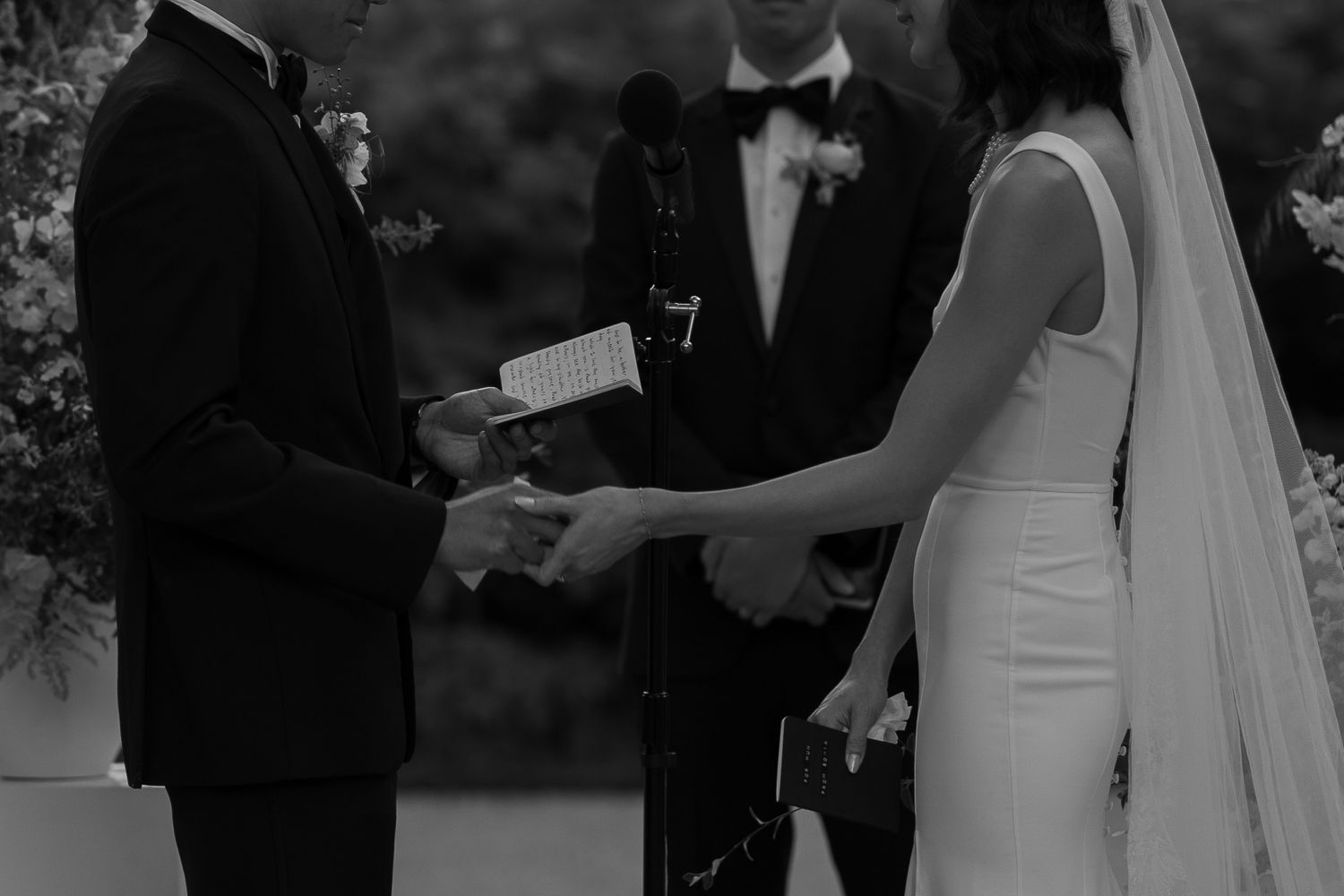 A black and white capture of a wedding ceremony showing the couple exchanging vows.
