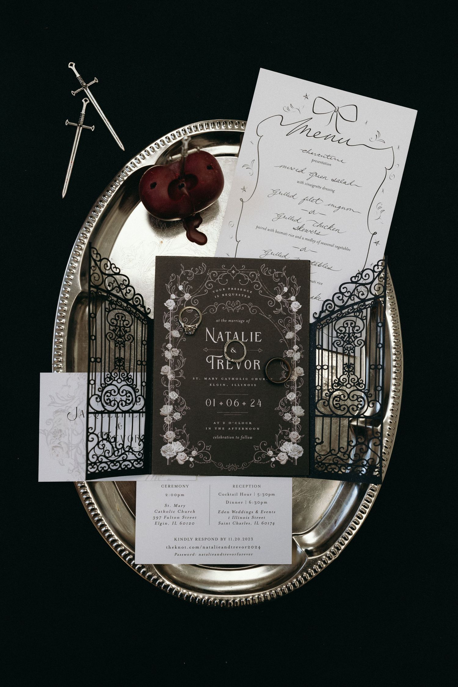 Dark moody wedding invitation suite with gothic gates design on silver tray.