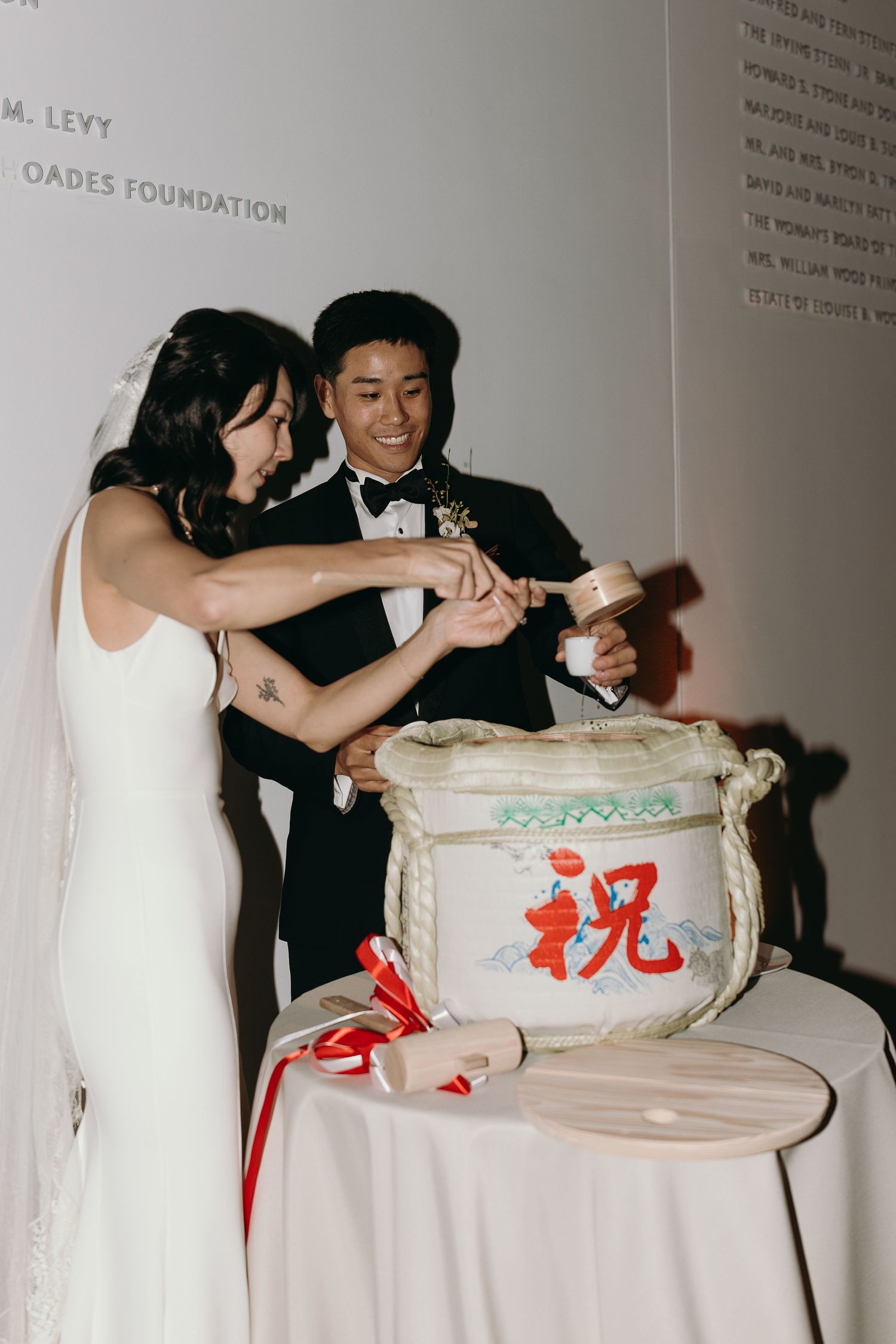 Wedding reception scene showing guests interacting with a decorative ceramic jar on a table.