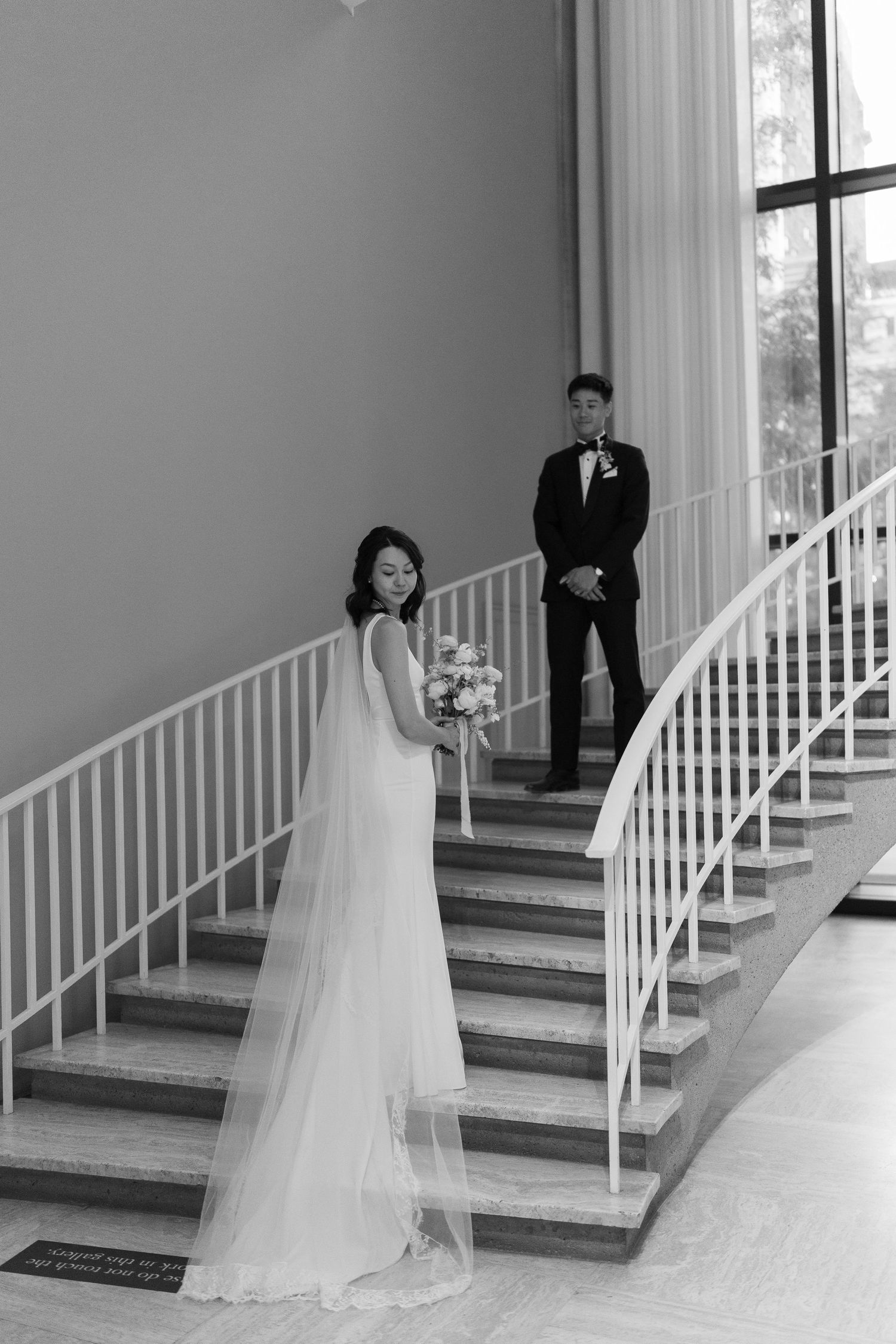 Elegant wedding photo on a curved white staircase in black and white.