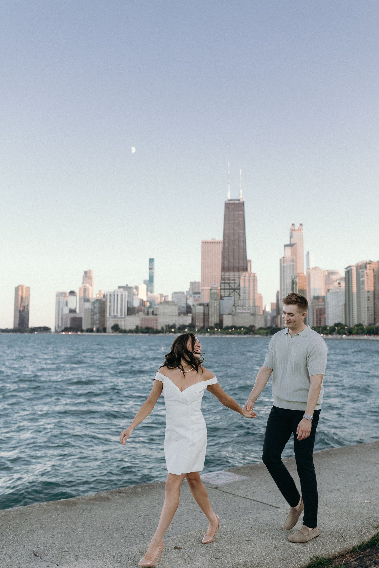 A couple spends a romantic evening along Lake Michigan with Chicago's iconic skyline in the background at sunset.