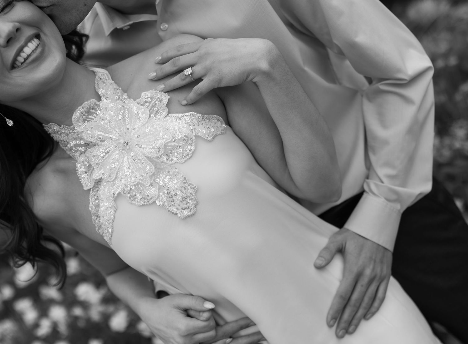 Black and white photo showing hands embracing a midsection wearing delicate lace detail.