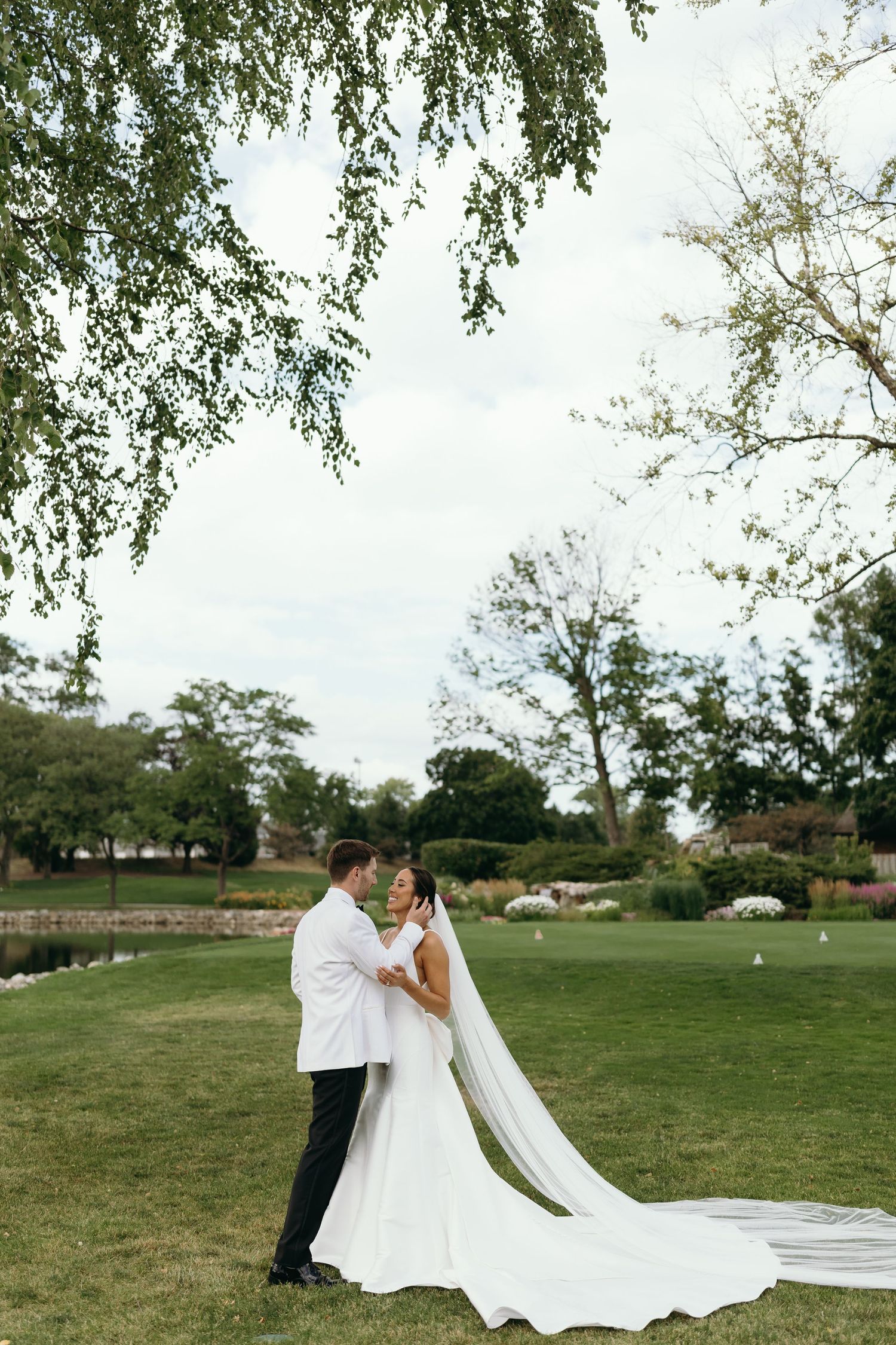 Romantic wedding portrait on a golf course with flowing white dress and veil.
