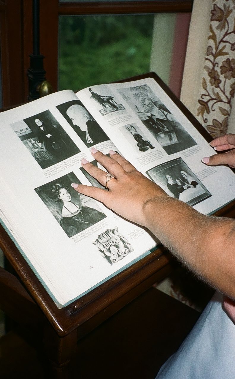 Someone's hands flip through a black and white photo album on a wooden surface near a window with natural light.