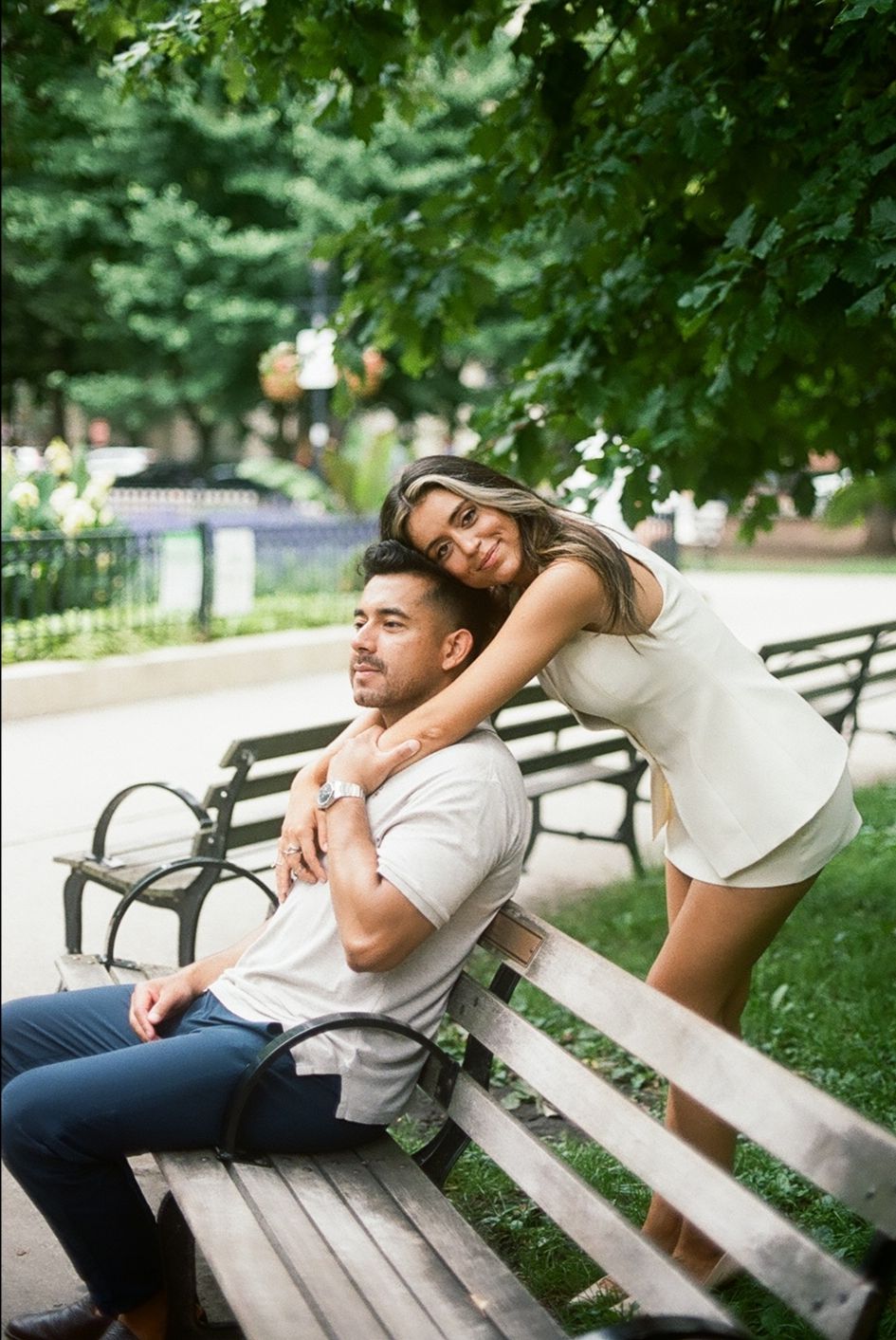 Playful couple relaxing on park bench under green tree canopy. Chicago Film Wedding Photographer, Gold Coast engagement
