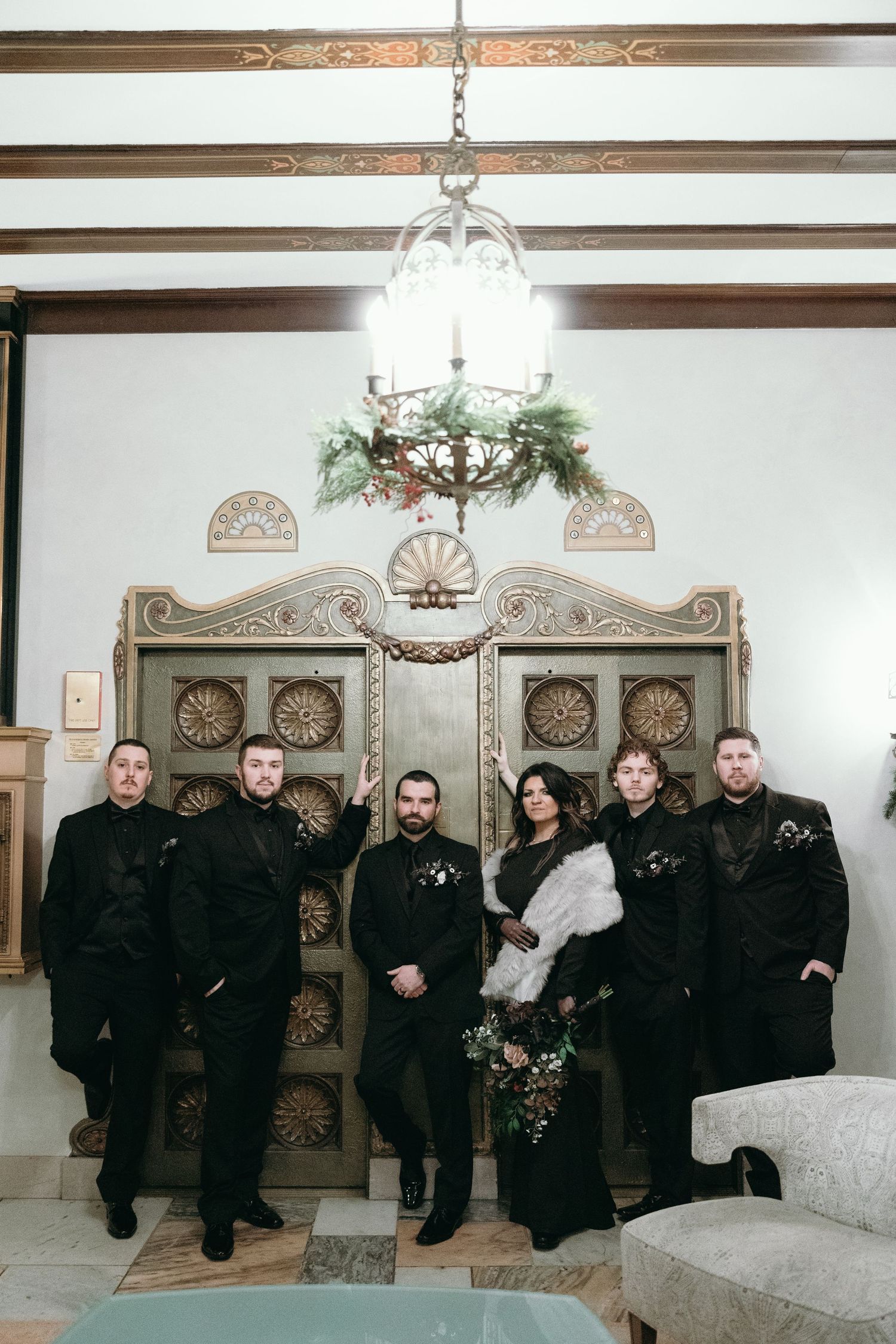Band members wearing black outfits pose together on a white couch for formal wedding photos.