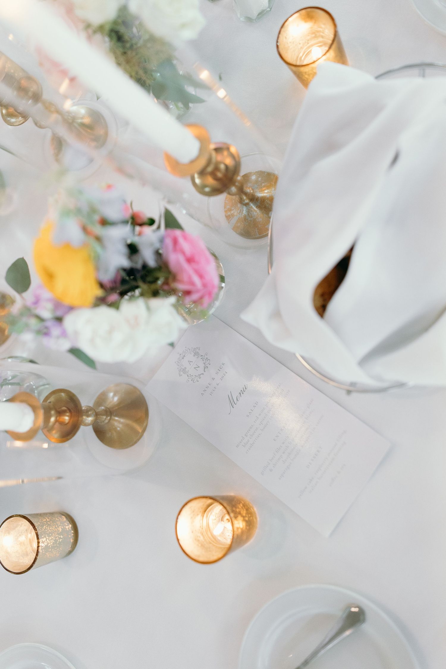 Overhead view of elegant wedding table setting with candles and floral centerpieces.