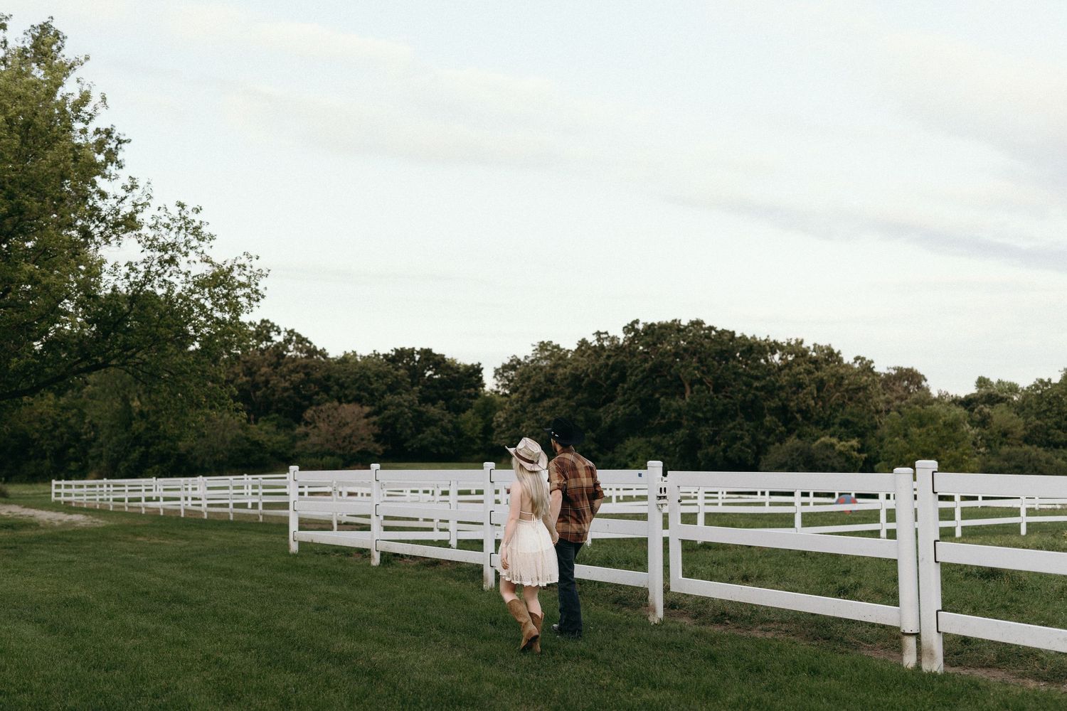 A panoramic series of romantic outdoor engagement photos taken along white wooden fences at a scenic farm setting.
