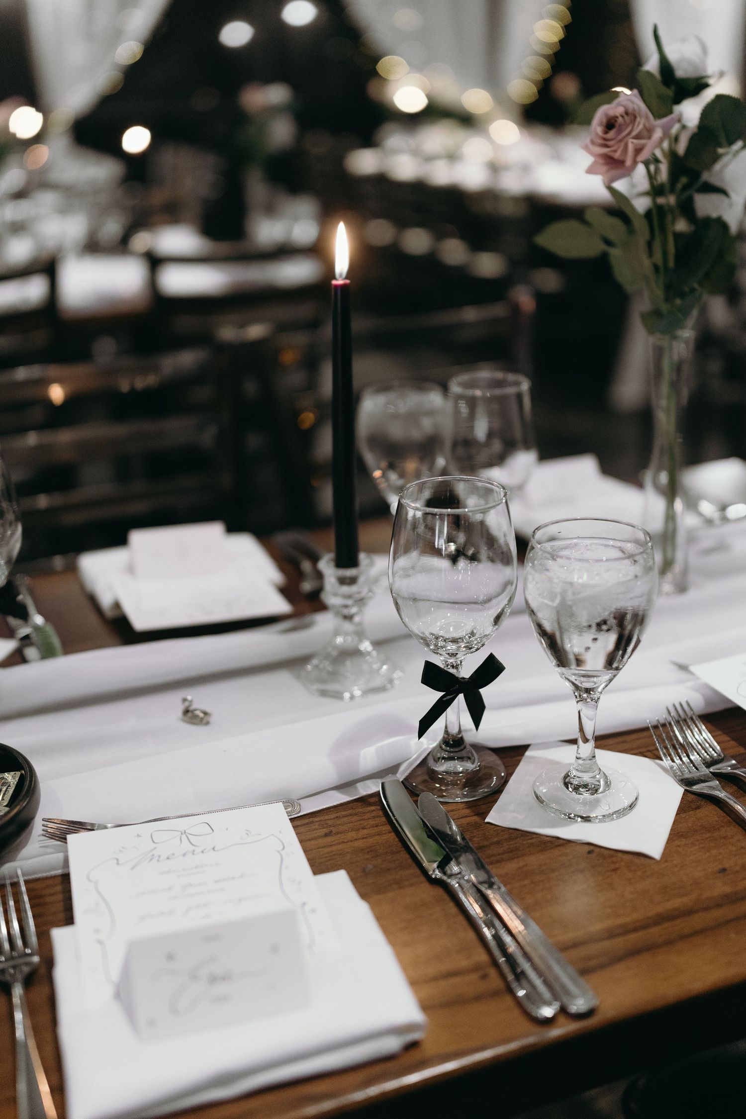 Elegant wedding table setting with black candle, wine glasses, and delicate place settings.