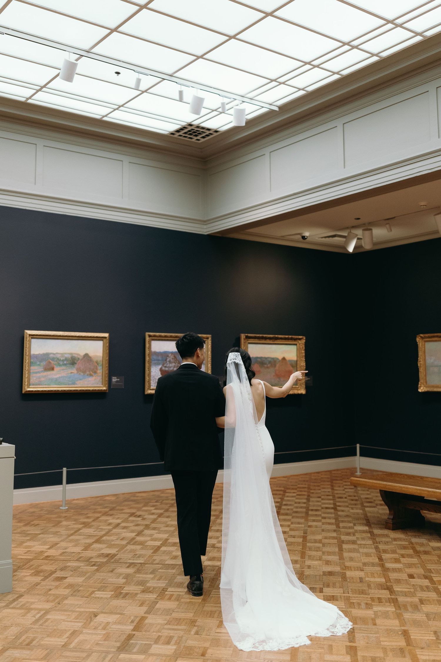 Couple viewing artwork in an art gallery with white ceiling and wood floors.