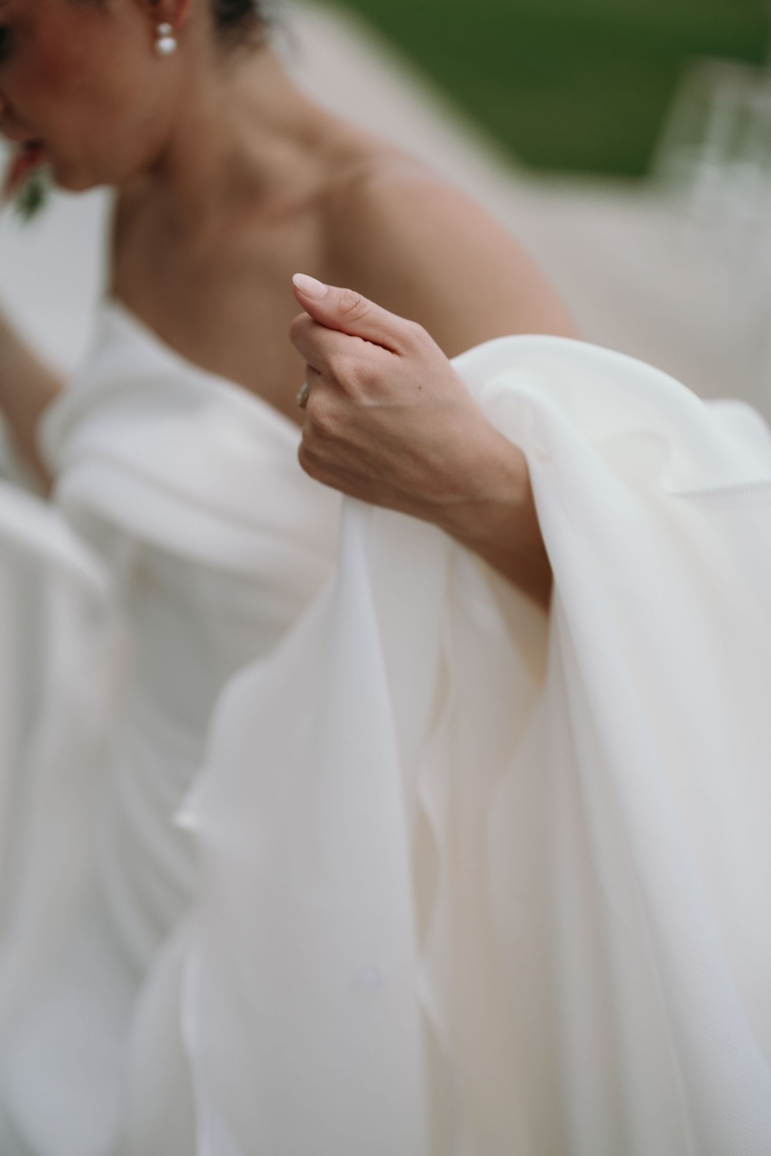 Graceful hand movements shown in sequence against soft white fabric and a blurred green background.