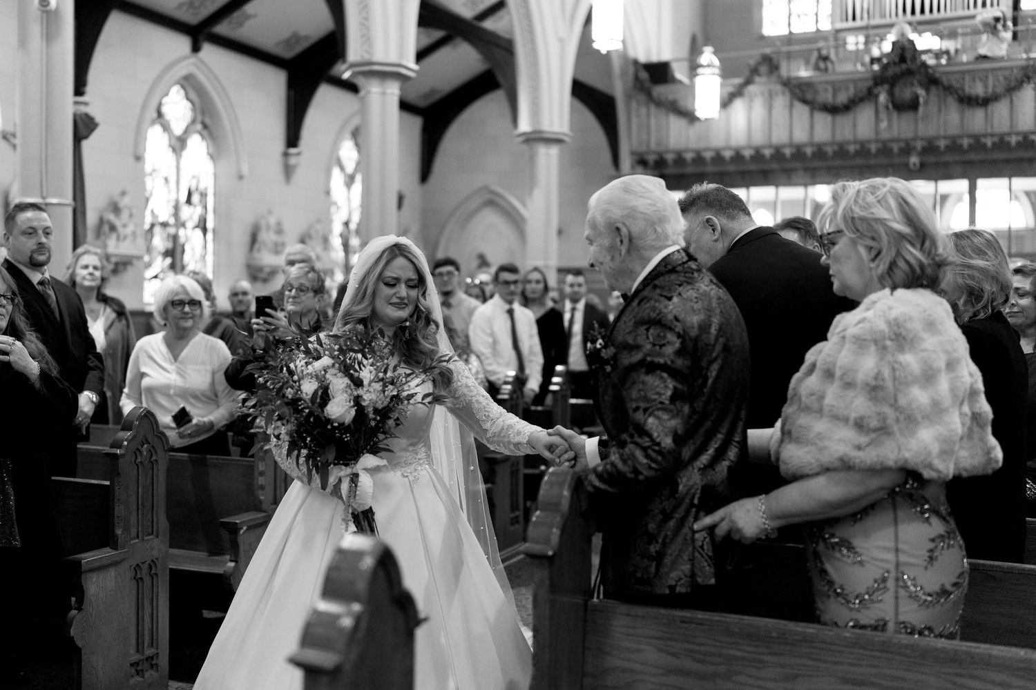 Black and white capture of a wedding ceremony in progress inside a traditional church setting.