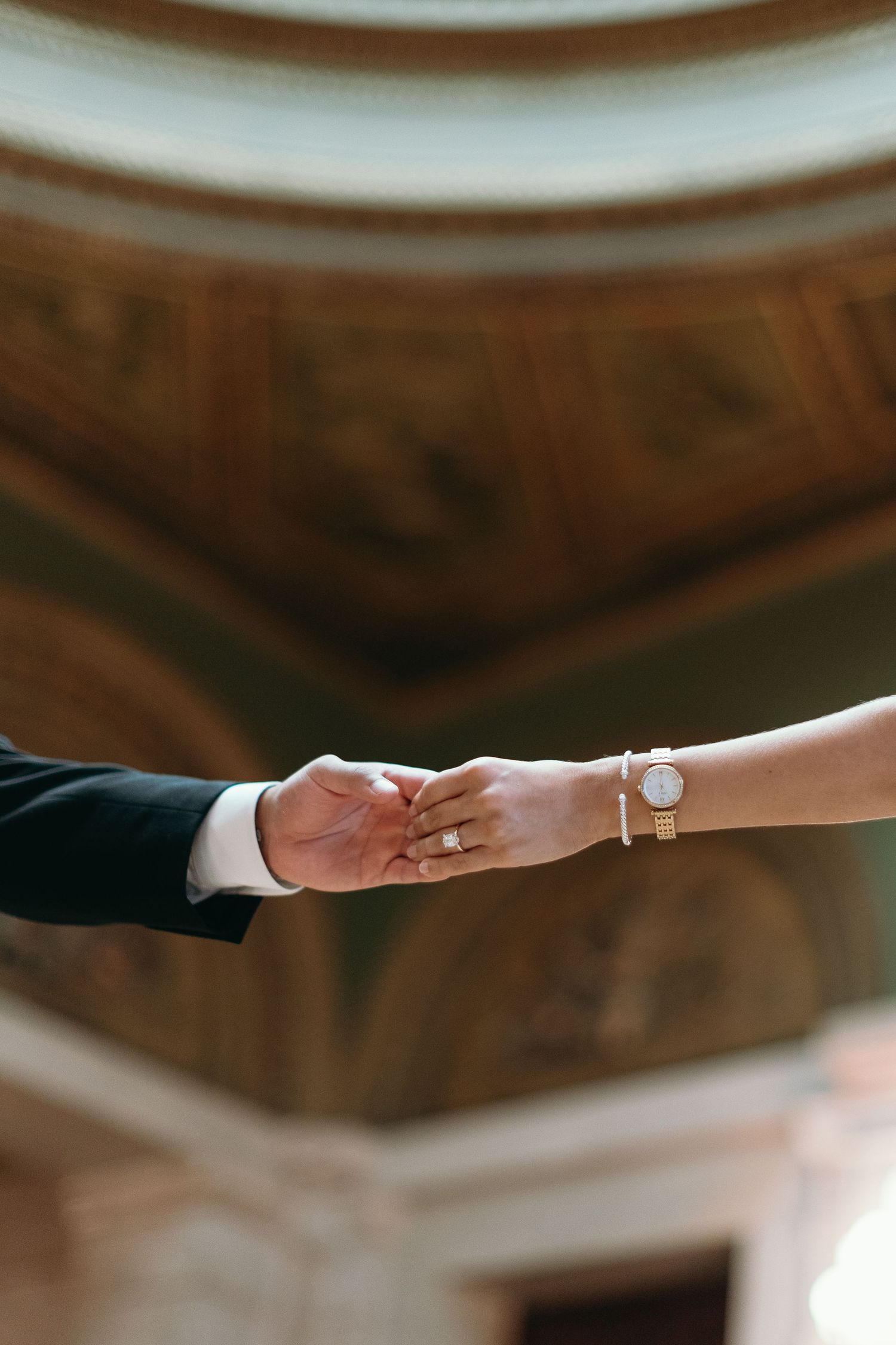 Close up of hands reaching toward each other showing wedding ring detail.
