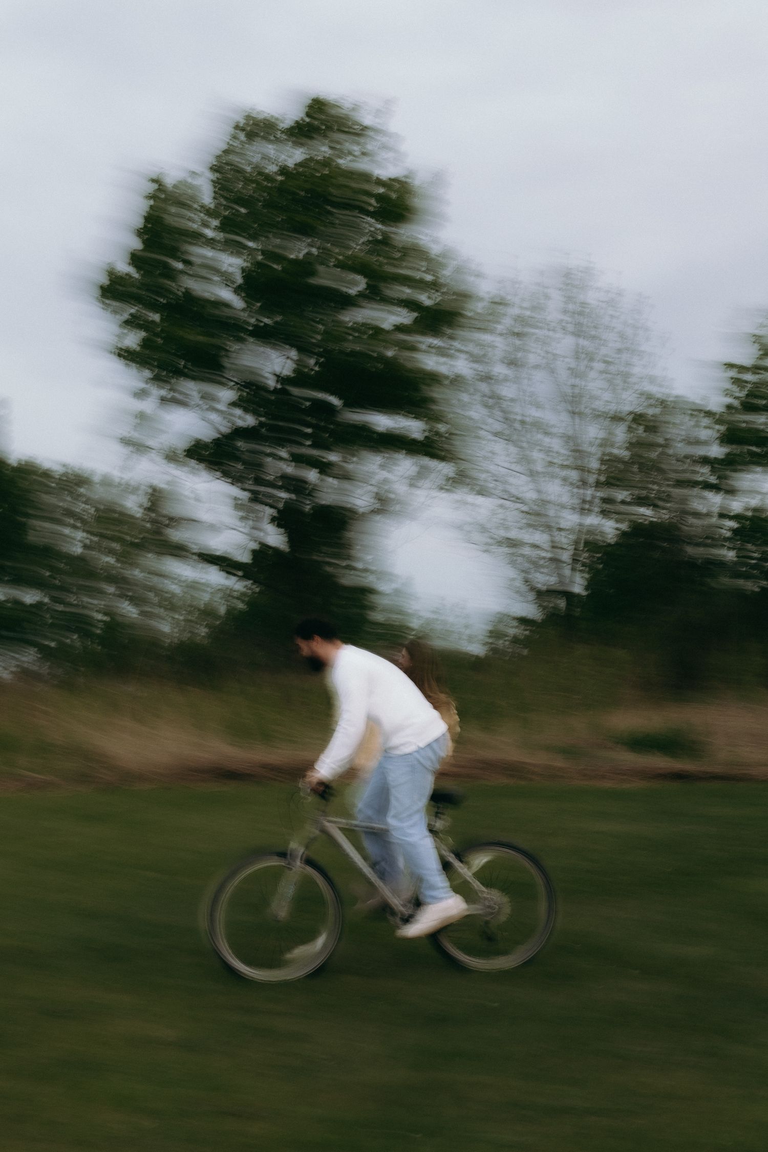 Person riding a bicycle through a green park, captured with motion blur effect showing speed and movement.
