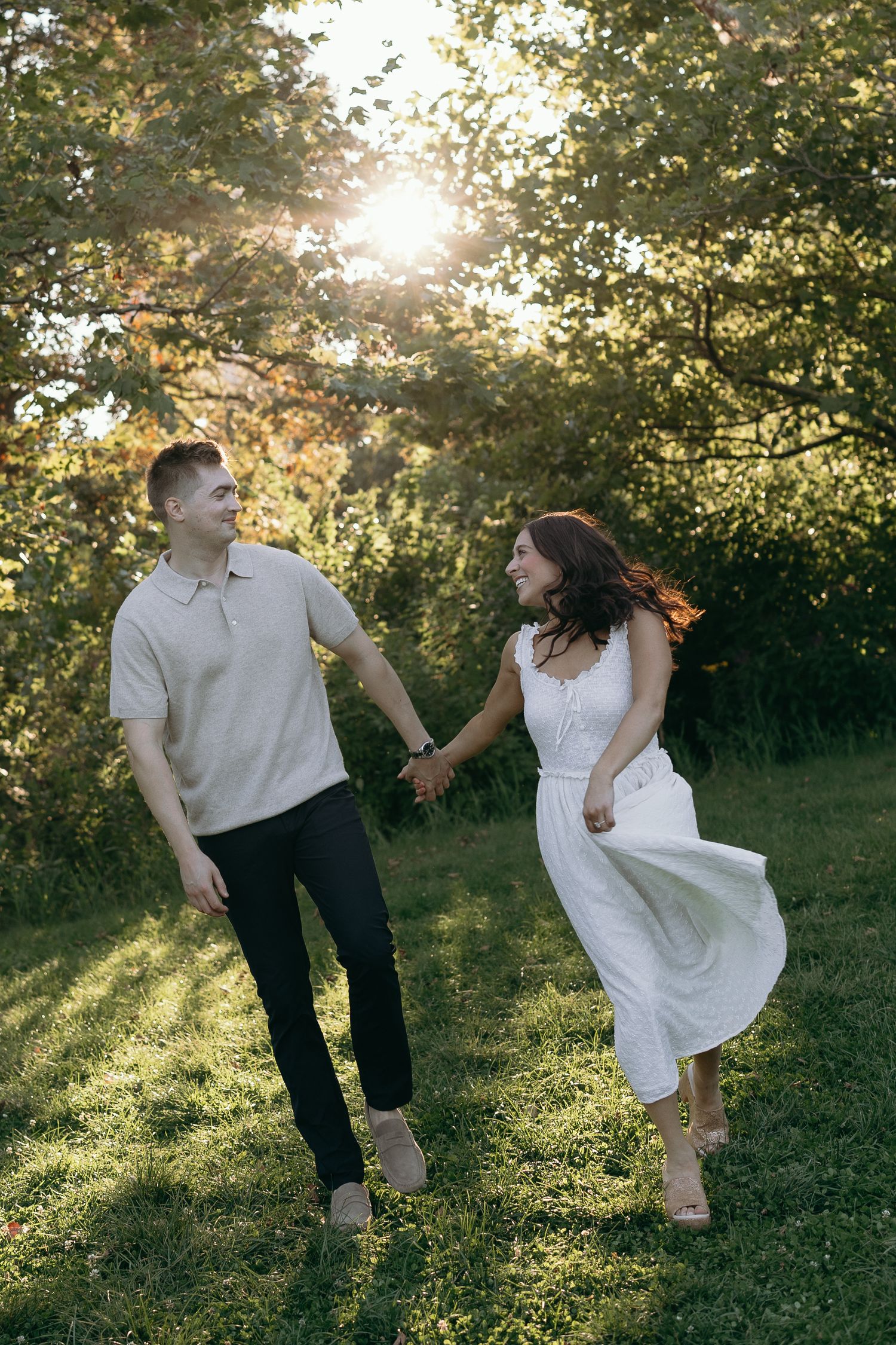 A couple dances together in a sunlit meadow at golden hour, creating a romantic and carefree atmosphere.