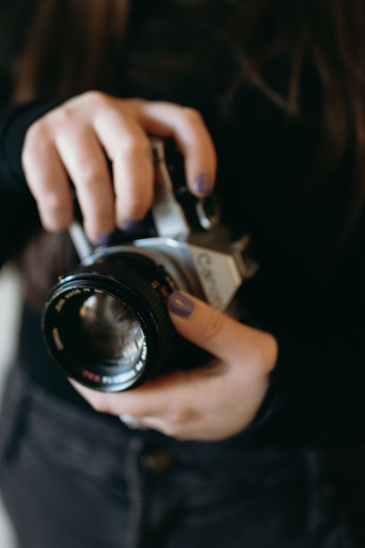 Close-up of hands holding a vintage camera with a large lens.
