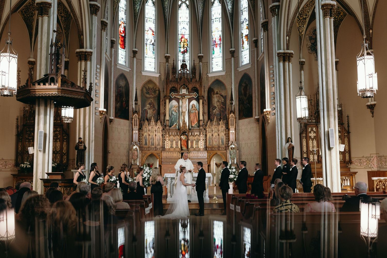 Grand cathedral wedding ceremony with gothic architecture and reflective flooring.