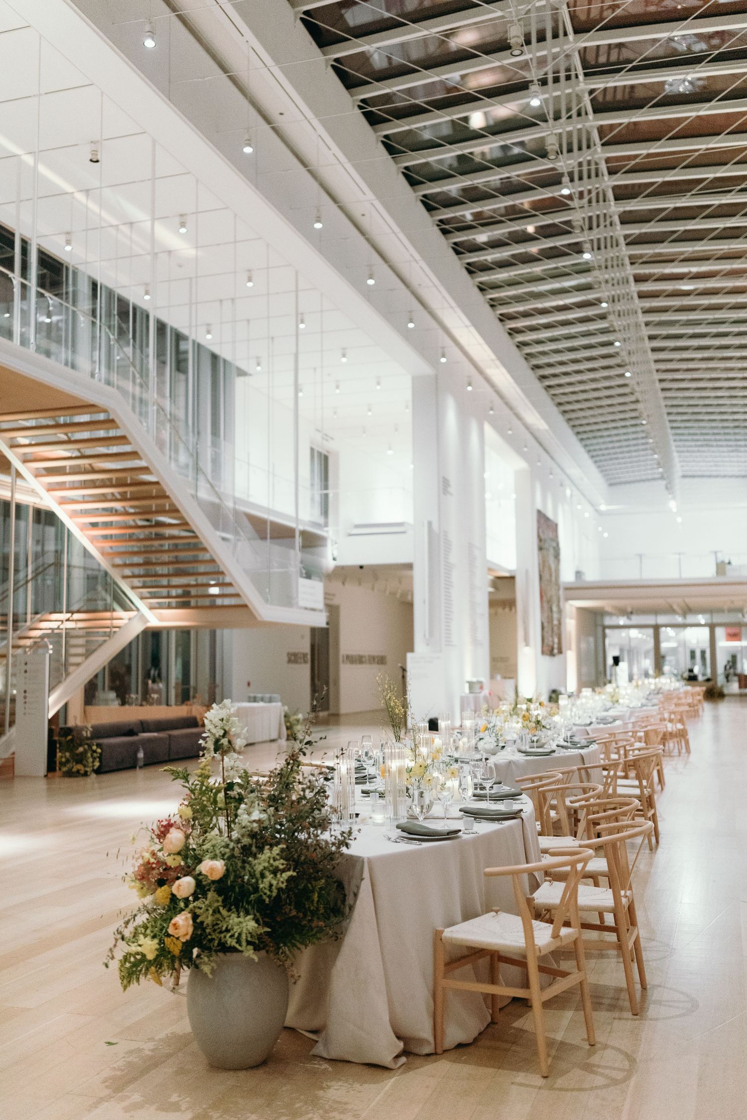 Modern wedding reception venue with floating staircase and elegant table settings.