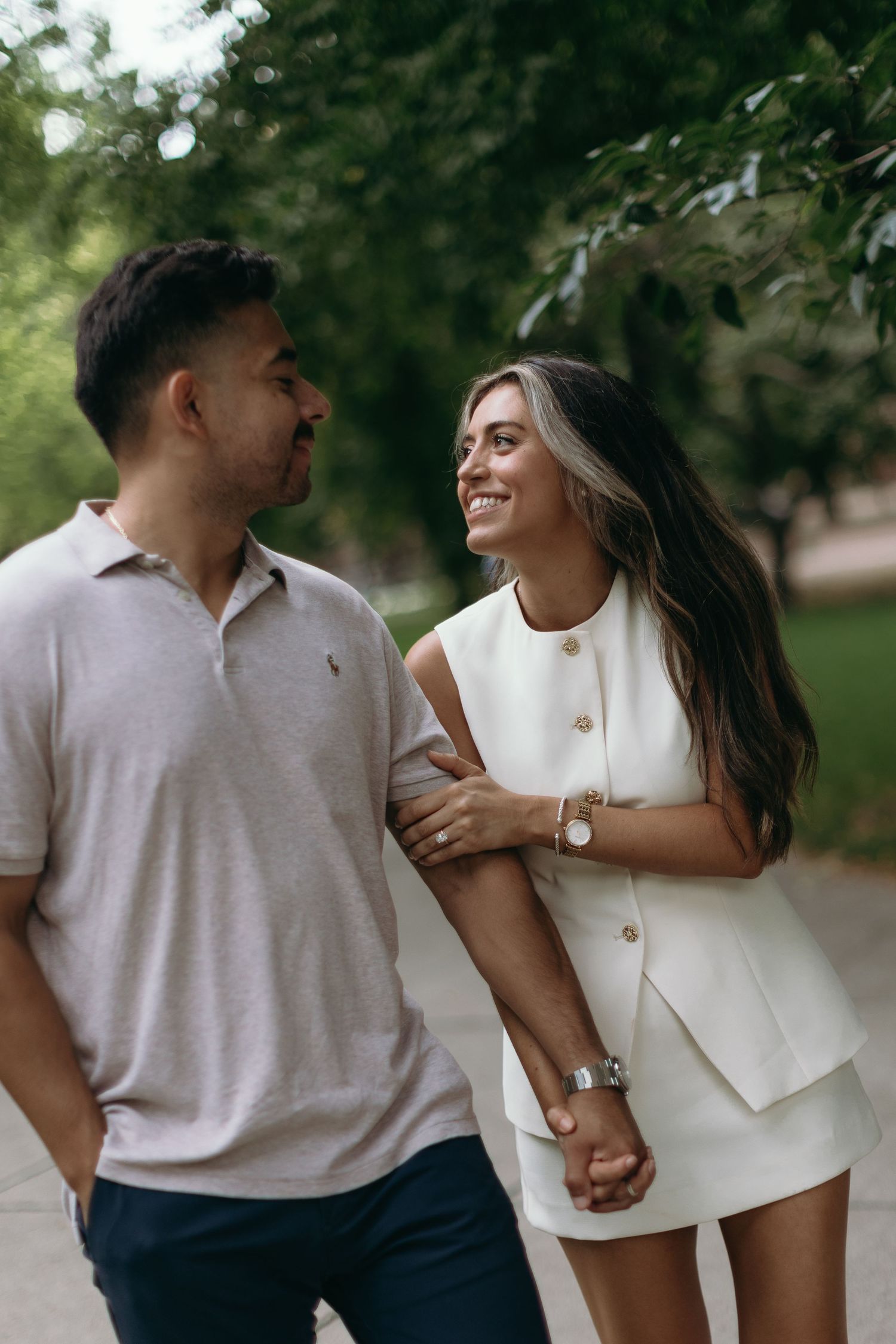 Couple in matching white and gray outfits hold hands and share intimate moments during outdoor photoshoot.