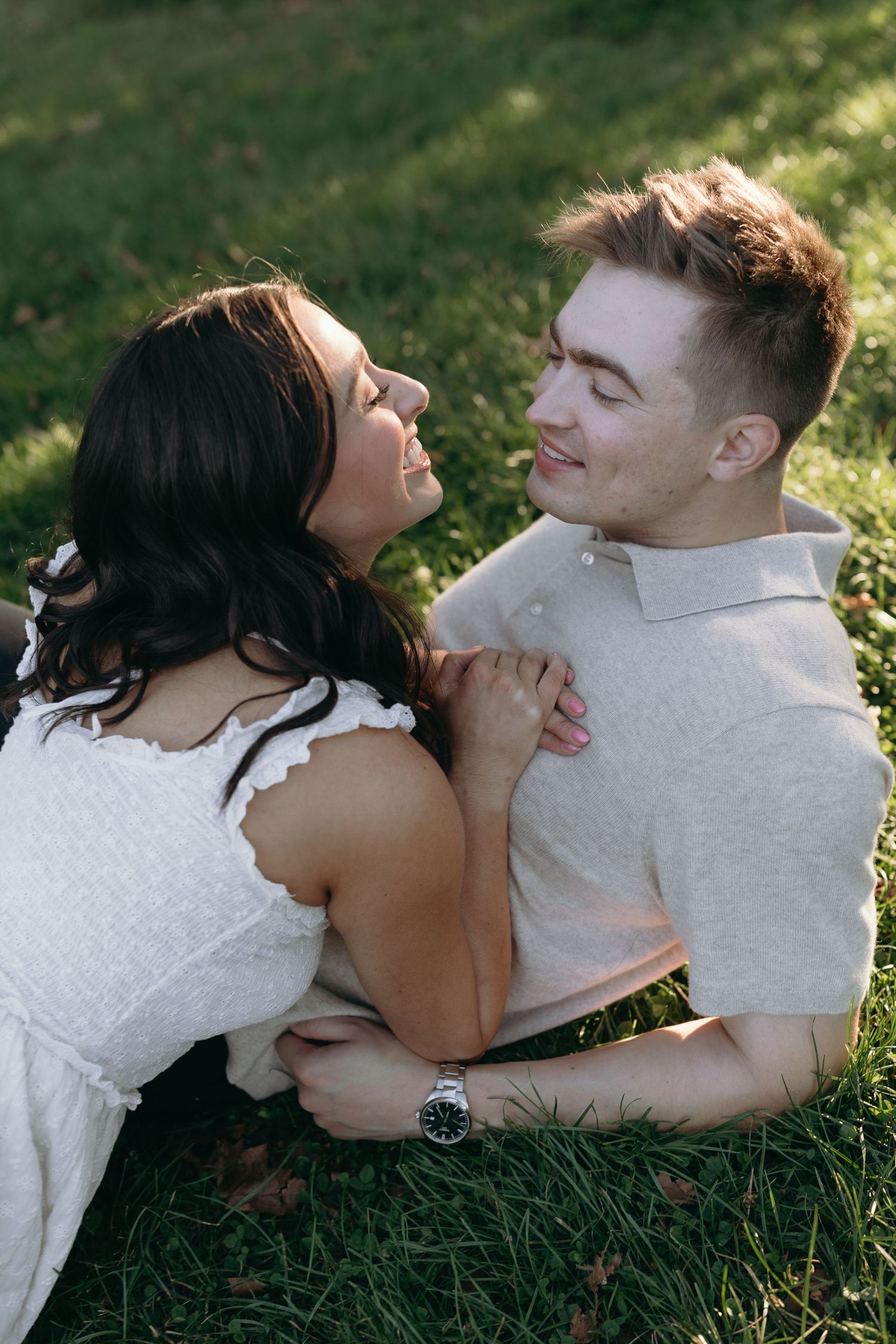 A couple lying together on green grass sharing intimate moments in nature.
