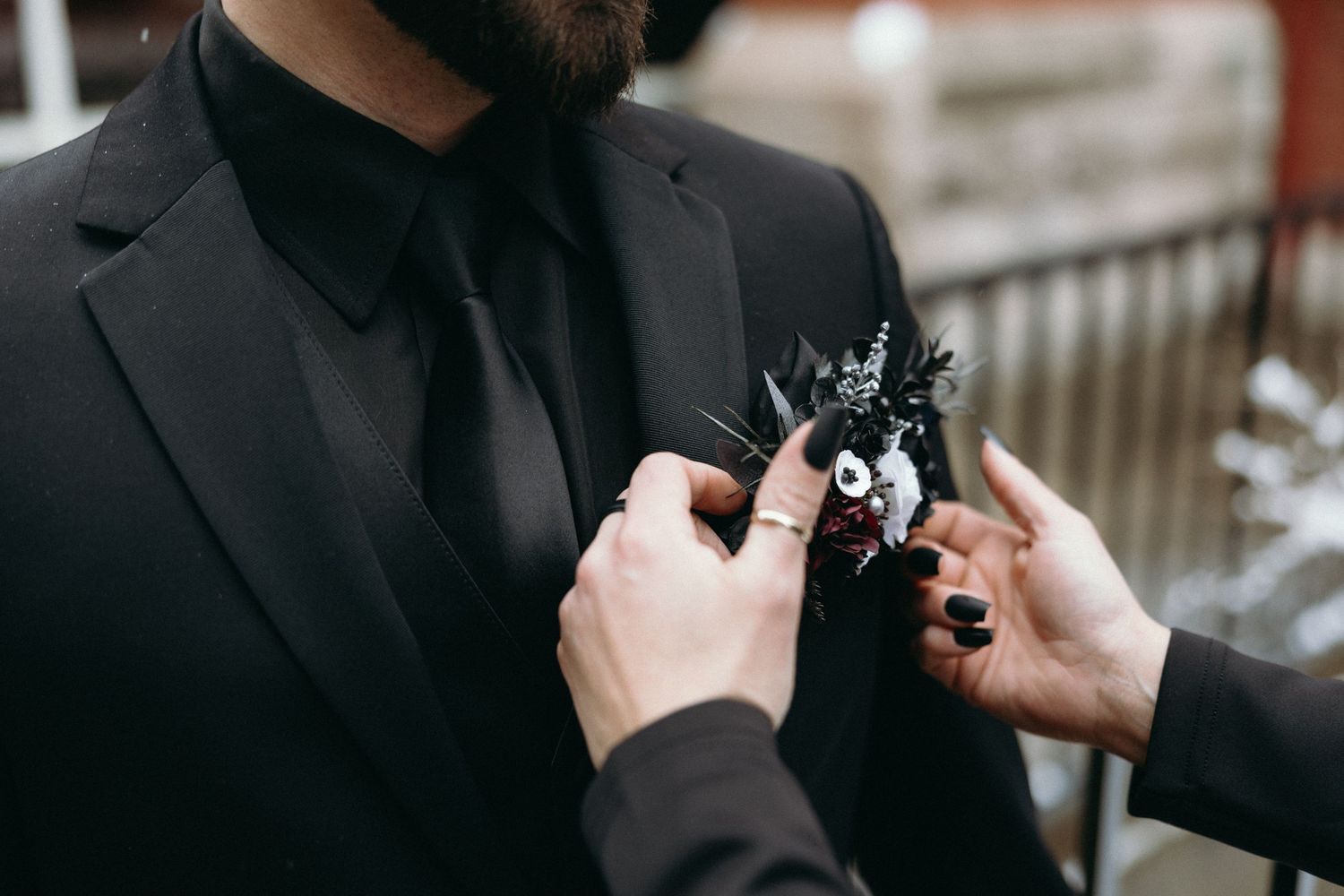 Hands adjusting details on formal black attire.