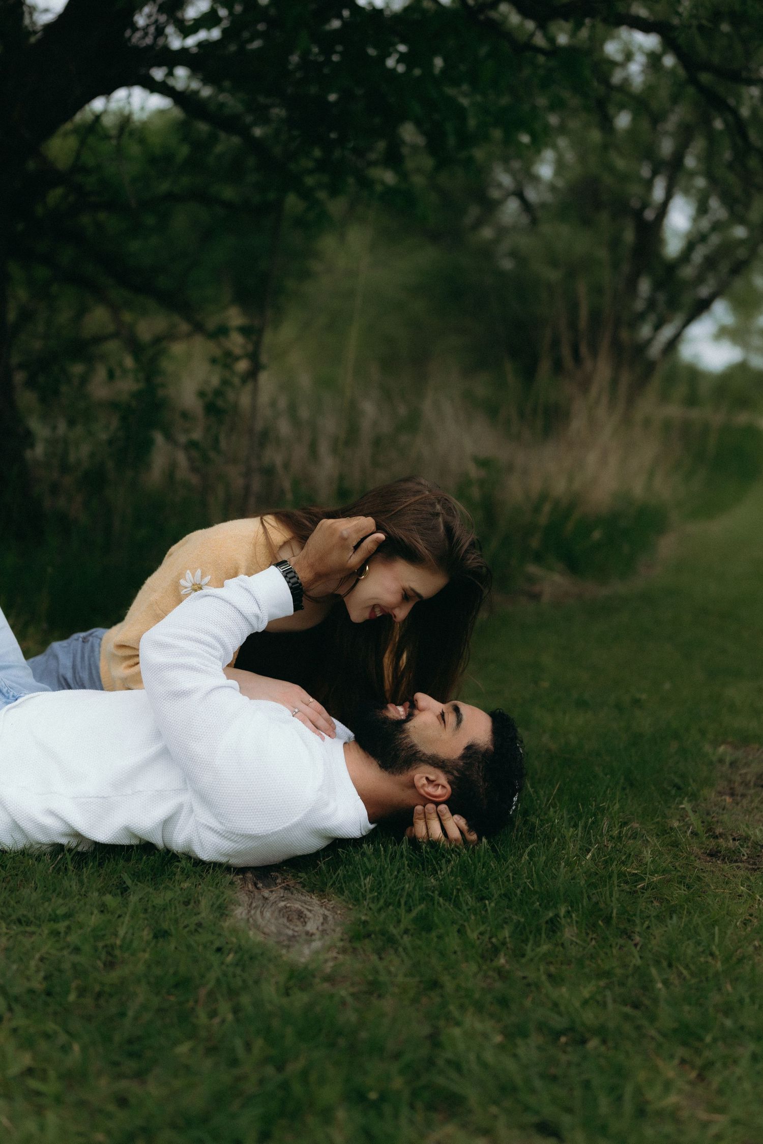 Chicago documentary engagemeA couple shares a romantic moment on green grass, with the woman leaning over the man in a lush outdoor setting.