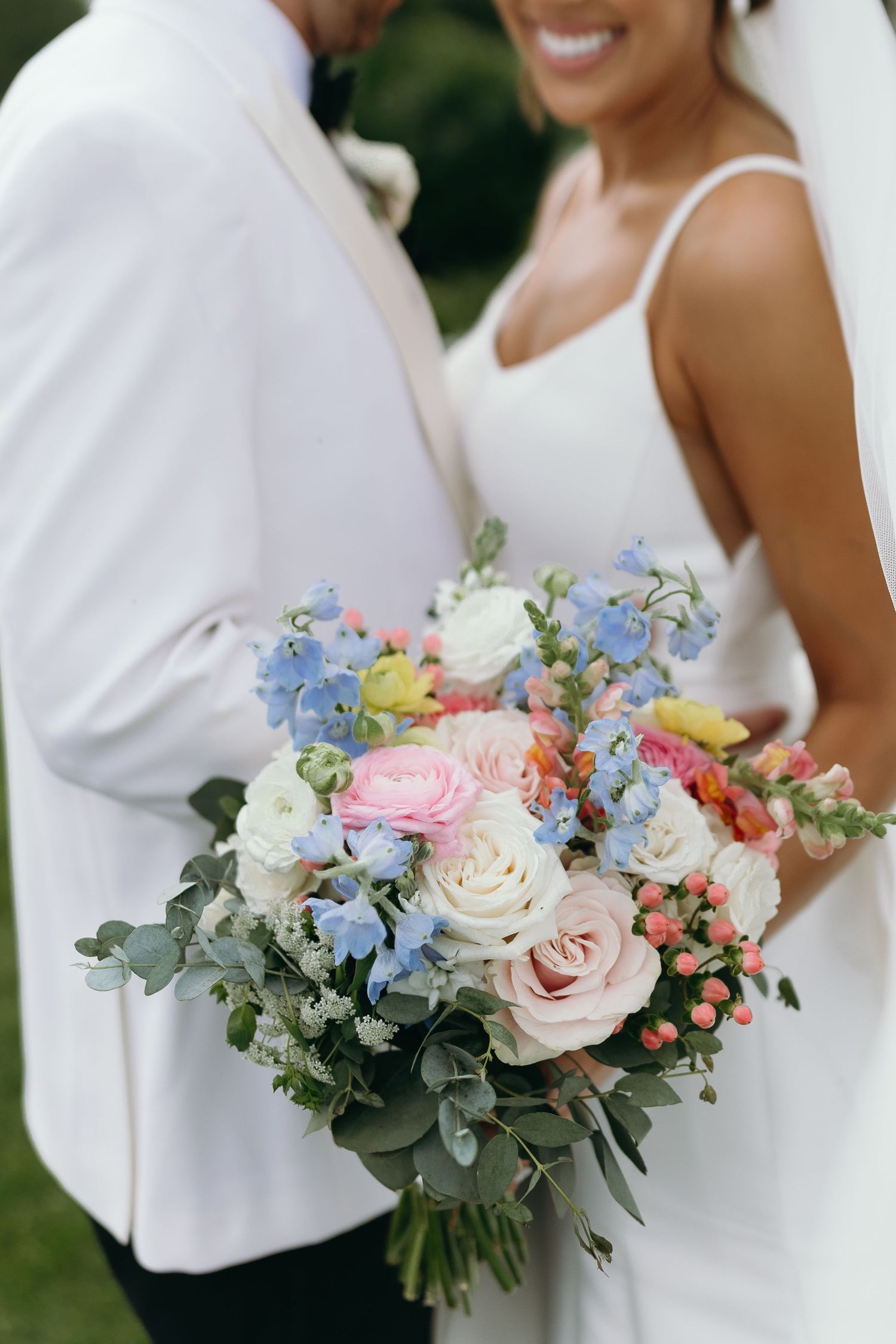 Beautiful pastel wedding bouquet with roses, eucalyptus and blue delphiniums.