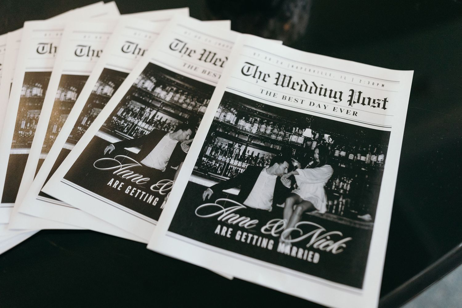 Multiple copies of The Wedding Post newspaper arranged in a moody dark setting.