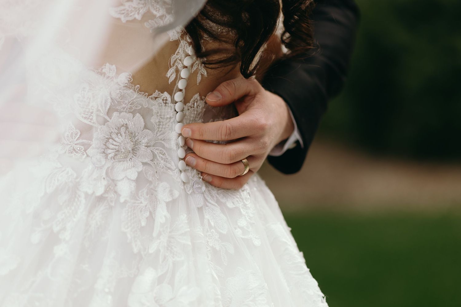 Close-up detail of intricate lace patterns and beading on a white wedding dress.