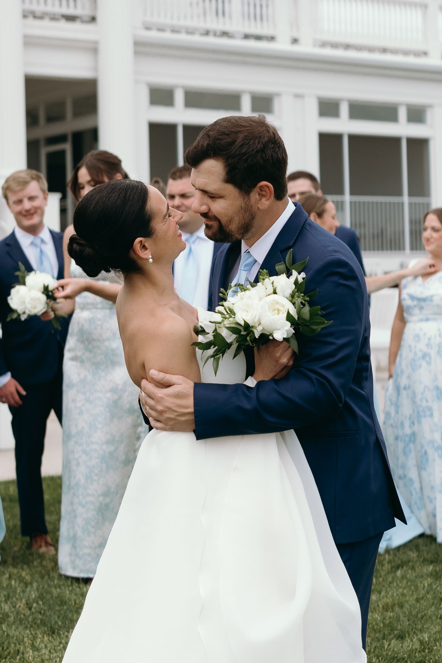 Elegant outdoor wedding reception with multiple candid moments showing guests and newlyweds on a lawn with white columns.