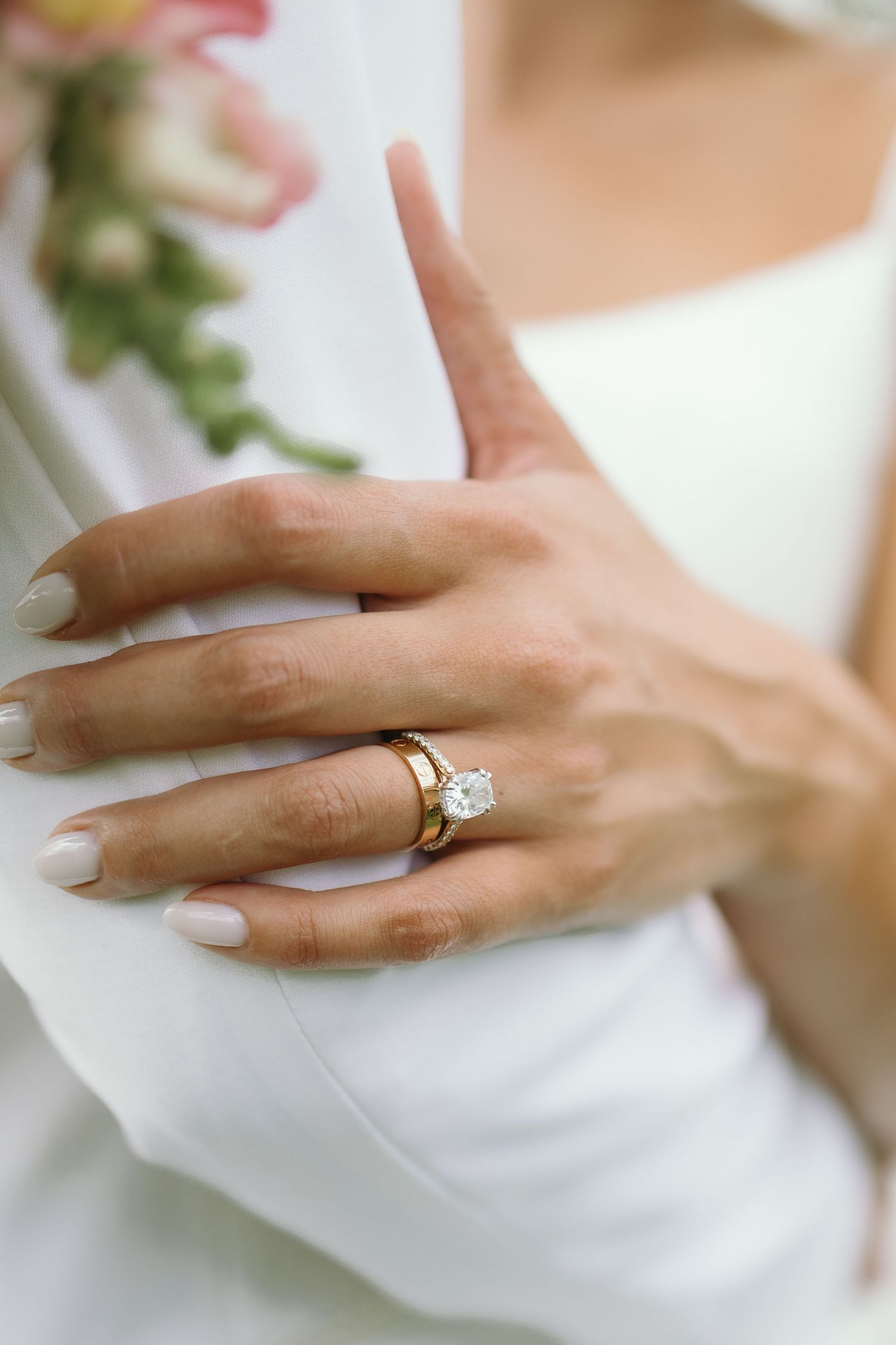 Close-up of engagement ring and wedding band on manicured hand.