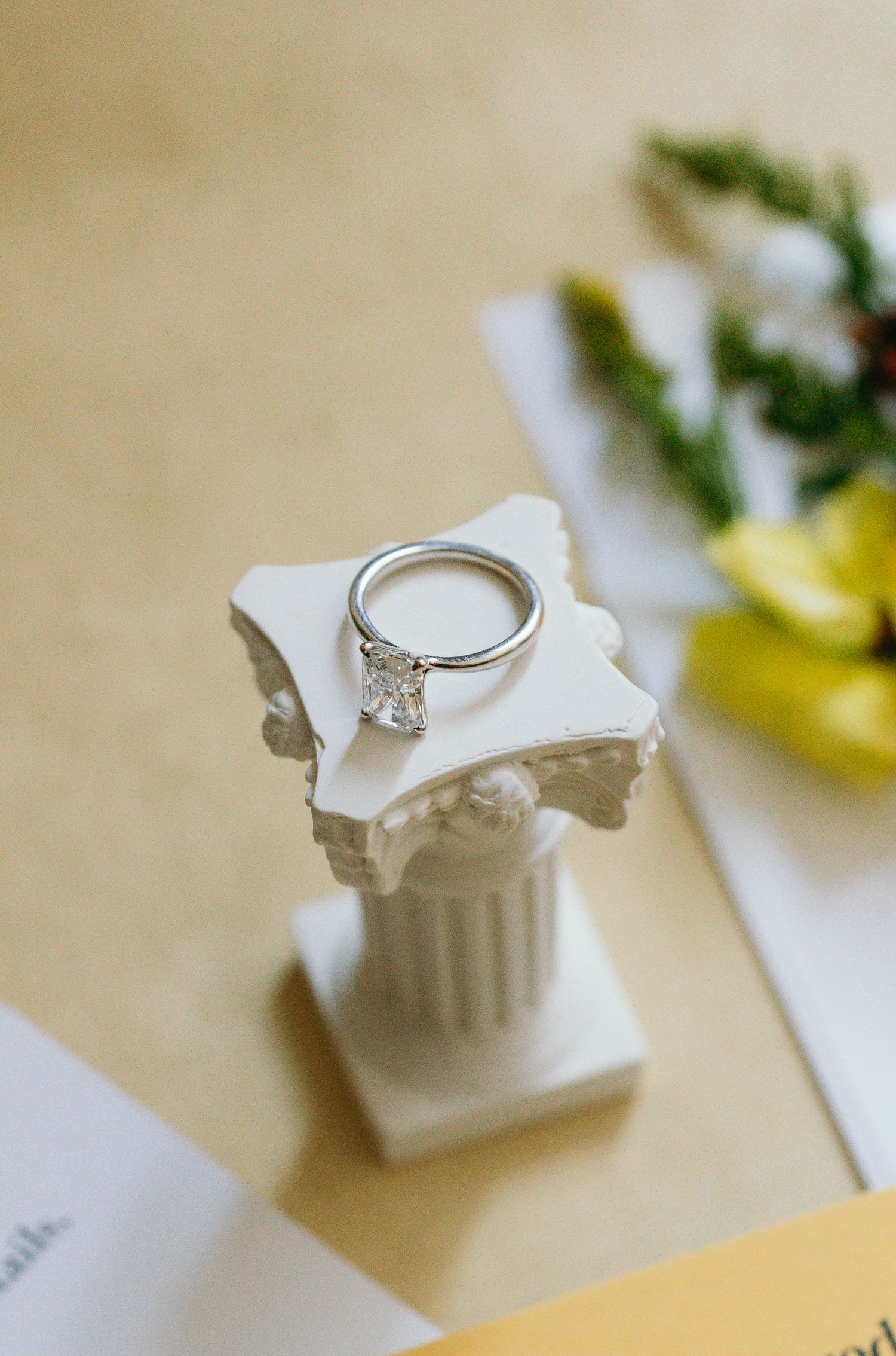 Diamond engagement ring displayed on small white decorative column.