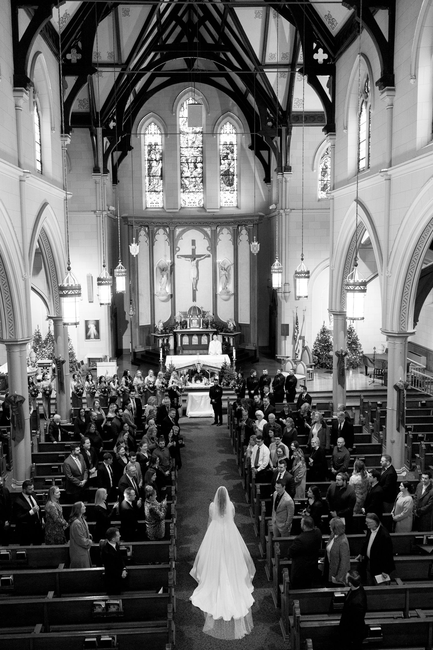 Black and white photo showing a grand church interior during a wedding ceremony with vaulted ceilings.
