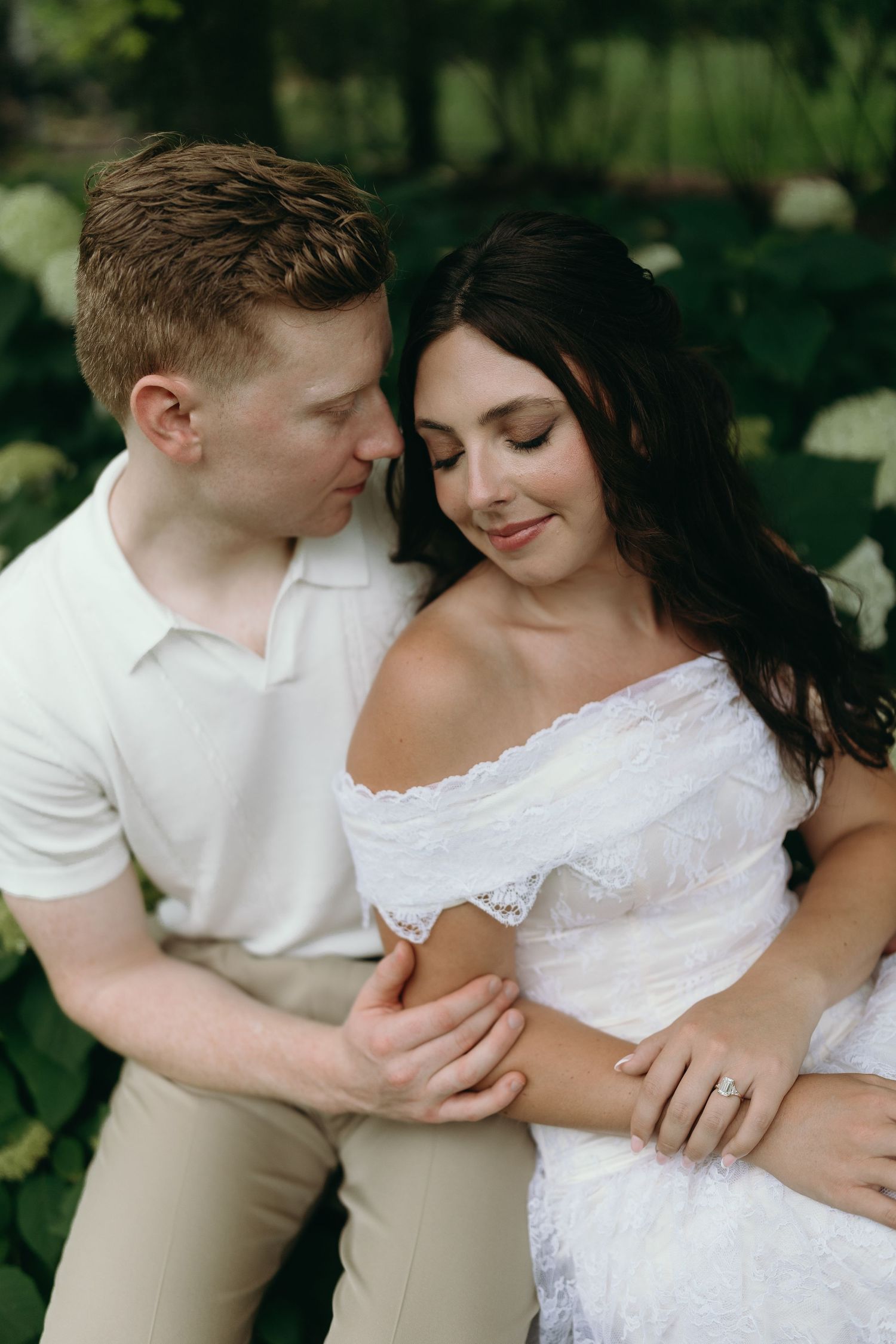 An intimate moment captured outdoors with white flowers and greenery in the background. The Villa Terrace Milwaukee