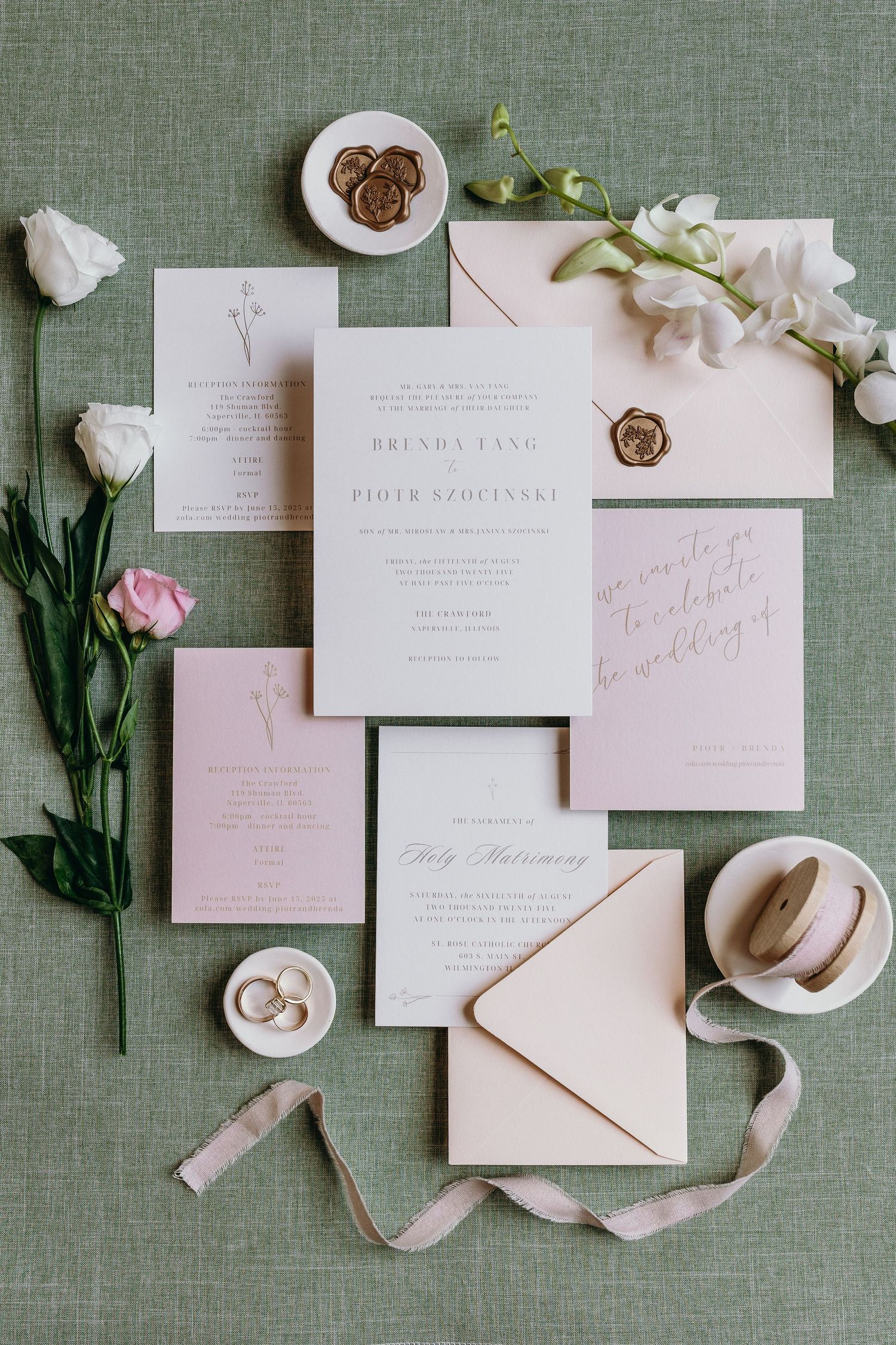 Elegant wedding stationery suite with pink and white invitations, flowers, and silk ribbon on sage green linen background.