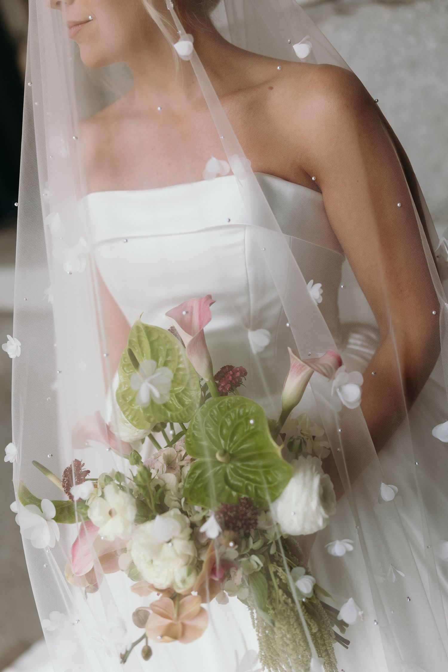 Close-up series of a bride in white dress holding a romantic bouquet with pink and green flowers.