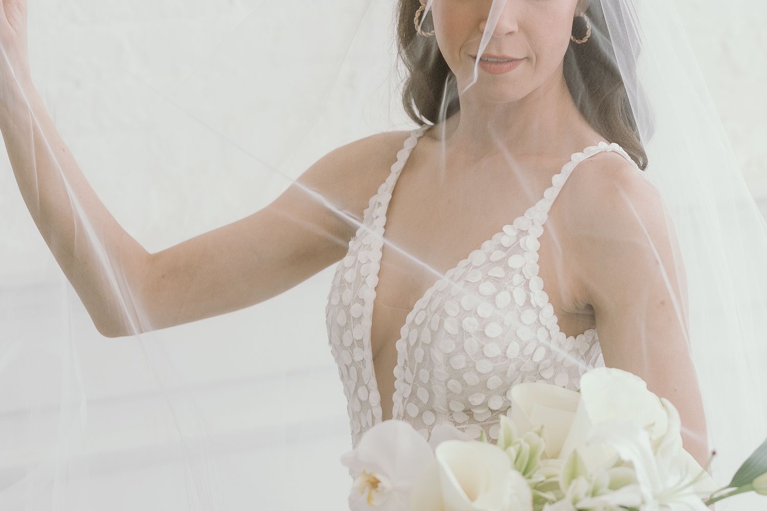 Woman in white wedding dress holding a bouquet of white flowers.