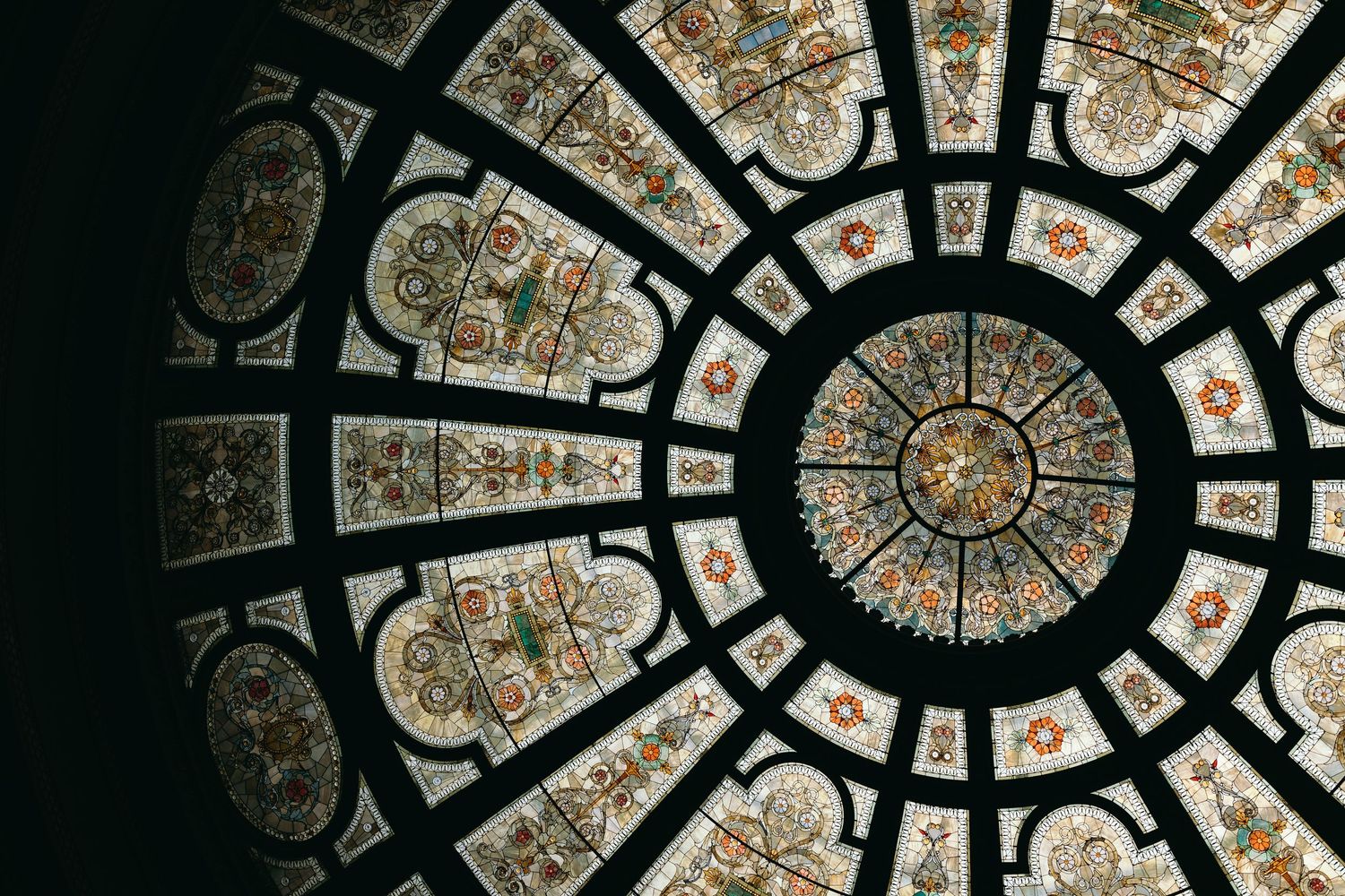 Aerial view of a dark spiraling fractal pattern with orange and white elements creating an abstract kaleidoscopic design.